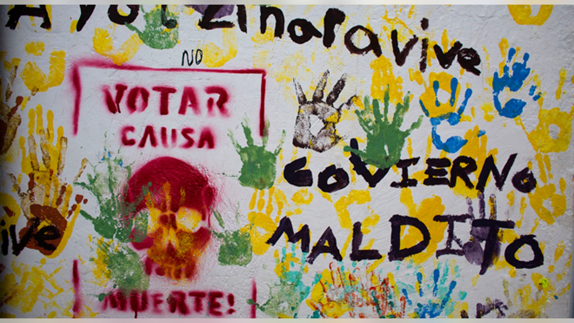 Graffiti in the central square of Tixtla, home of the rural normal school at Ayotzinapa, reads "Ayotzinapa lives. Voting causes death. Cursed government," in Tixtla, Mexico, Saturday, June 6, 2015. A day ahead of elections, a community group, many with faces covered by bandanas, stopped all traffic entering and leaving the Guerrero state town of Tixtla along one main road, to search for and burn any campaign or election materials. (AP Photo/Rebecca Blackwell)