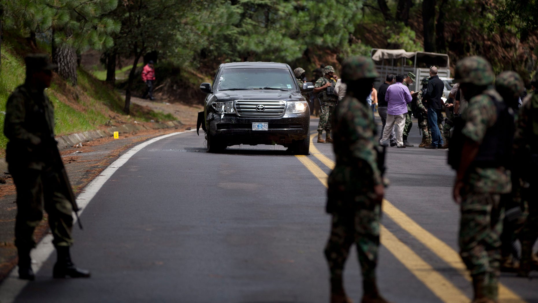 Military personal stand guard around an armored U.S. Embassy vehicle after it was attacked by unknown assailants on the highway leading to the city of Cuernavaca, near Tres Marias, Mexico, Friday, Aug. 24, 2012. Two U.S. government employees were shot and wounded in an attack on their vehicle south of Mexico City on Friday, a law enforcement official said. (AP Photo/Alexandre Meneghini)