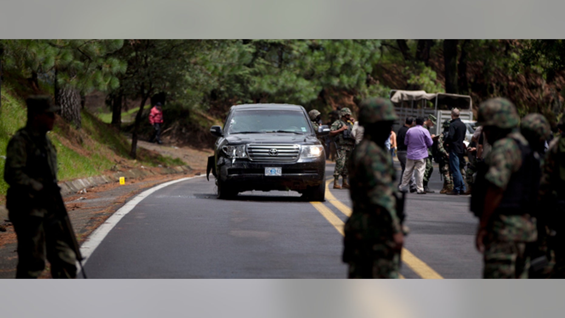 Military personal stand guard around an armored U.S. Embassy vehicle after it was attacked by unknown assailants on the highway leading to the city of Cuernavaca, near Tres Marias, Mexico, Friday, Aug. 24, 2012. Two U.S. government employees were shot and wounded in an attack on their vehicle south of Mexico City on Friday, a law enforcement official said. (AP Photo/Alexandre Meneghini)