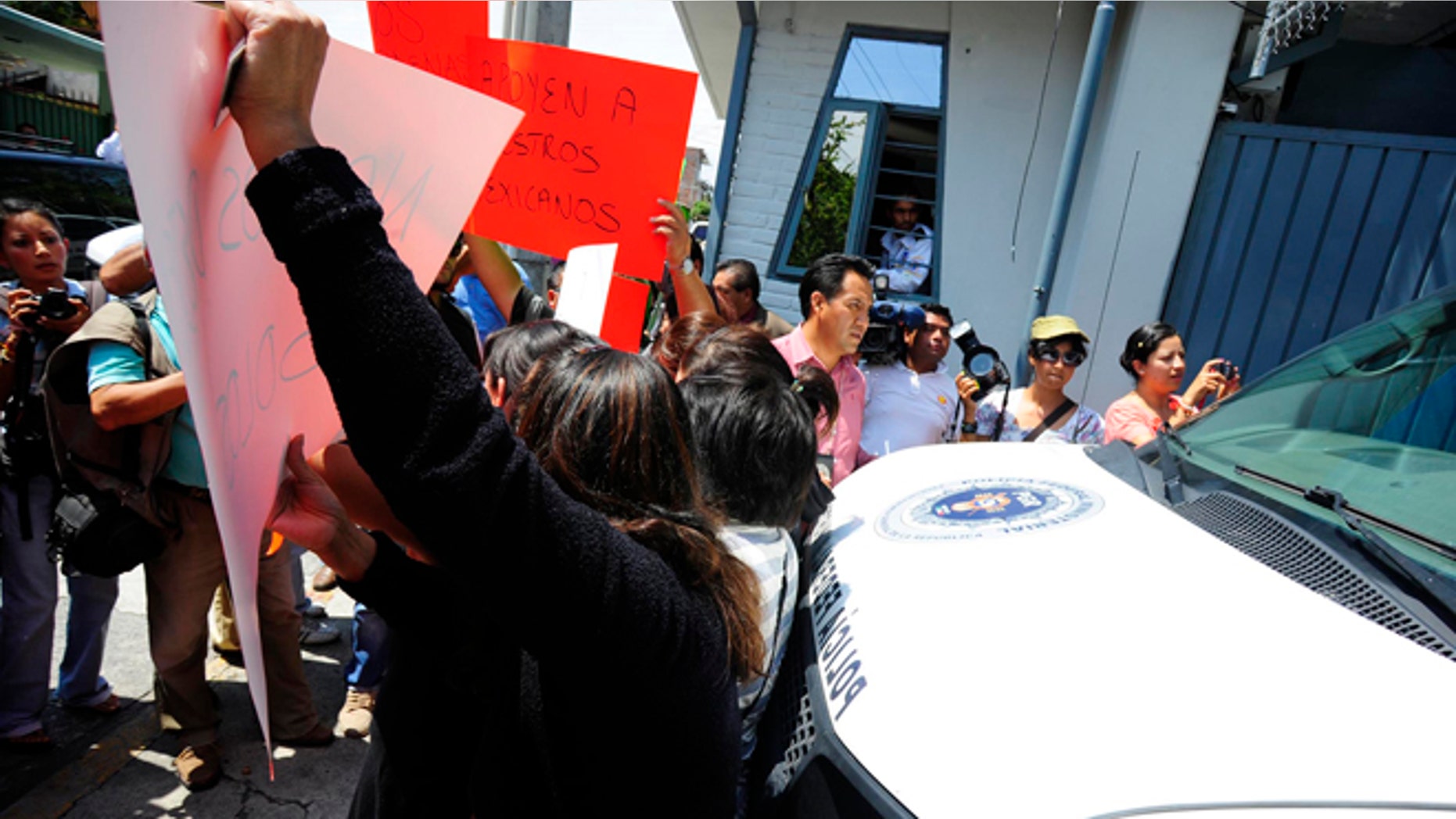Relatives of the federal policemen involved in last week's shooting against a U.S. embassy vehicle try to block the exit of a van carrying the officers to a federal detention center outside of the Attorney General's office in the city of Cuernavaca, Mexico, Monday Aug. 27, 2012. A judge ruled Monday that the 12 police officers accused of opening fire on a U.S. embassy vehicle and wounding two embassy employees should remain in detention in an incident that has roiled U.S./Mexican relations and drawn fresh attention to serious problems inside Mexico's premier law-enforcement agency. (AP Photo/Tony Rivera)