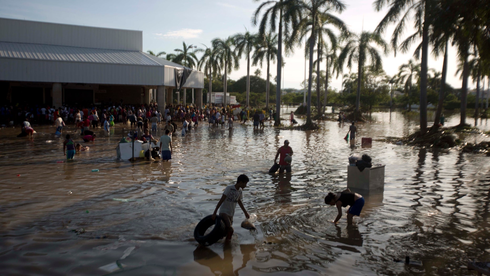 People wade through waist-high water in a store's parking, looking for valuables, south of Acapulco, in Punta Diamante, Mexico, Wednesday, Sept. 18, 2013. Mexico was hit by the one-two punch of twin storms over the weekend, and the storm that soaked Acapulco on Sunday - Manuel -re-formed into a tropical storm Wednesday, threatening to bring more flooding to the country's northern coast. With roads blocked by landslides, rockslides, floods and collapsed bridges, Acapulco was cut off from road transport. (AP Photo/Eduardo Verdugo)