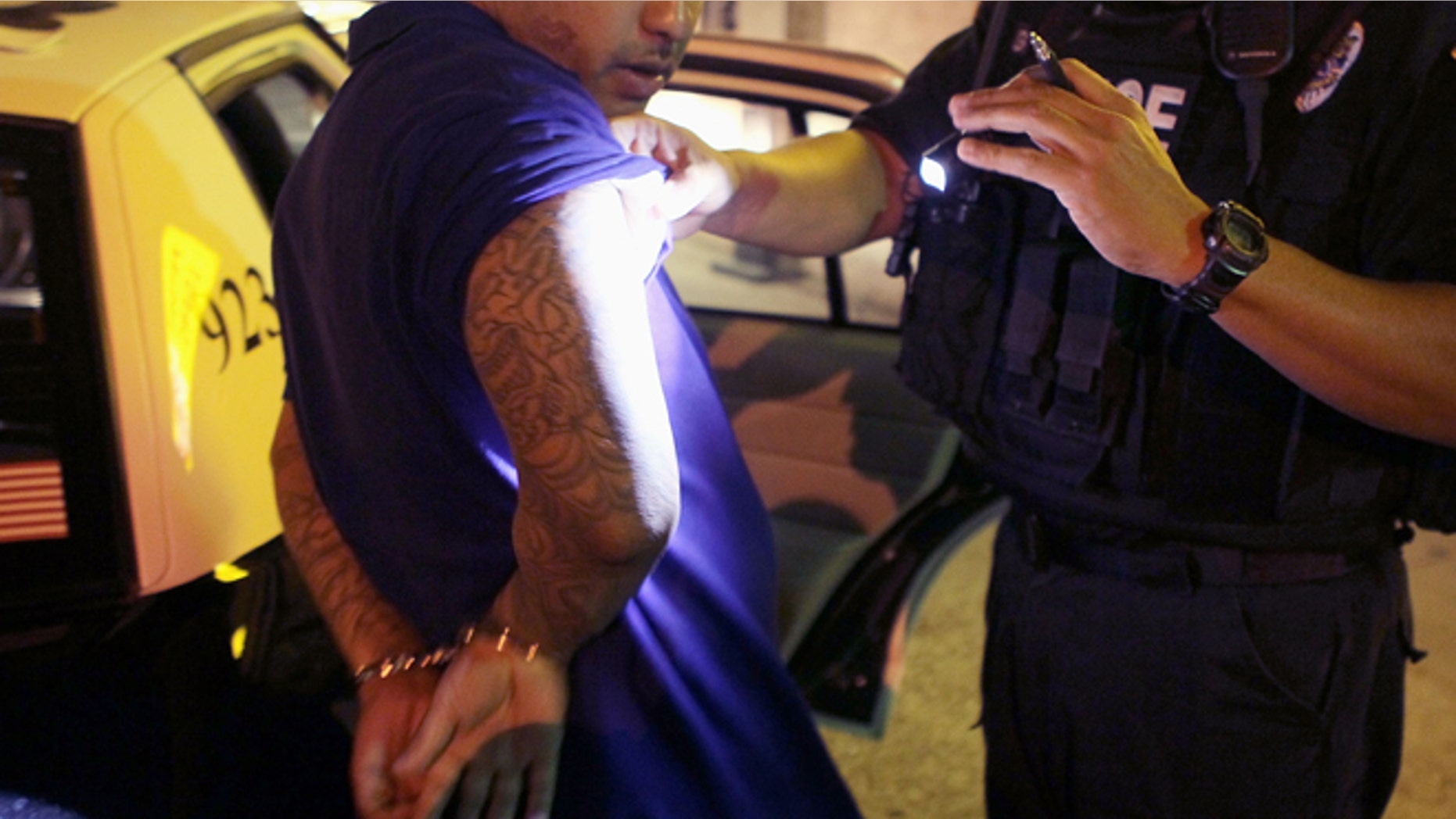 TUCSON, AZ - JUNE 03: Leon Gutierrez of the Tucson Police Department's Gang Tactical Unit looks over a suspect's tattoos for signs of gang affiliation following an altercation outside a currency exchange on June 3, 2010 in Tucson, Arizona. The Tucson Police Department is currently gearing up to begin training its officers on the implementation of the states controversial new immigration law SB 1070. Among other things the new law makes it a state crime to be an "unauthorized alien" or to knowingly harbor, hire or transport an unauthorized alien. A Tucson police officer was one of the first to file suit in federal court challenging the new law. (Photo by Scott Olson/Getty Images)