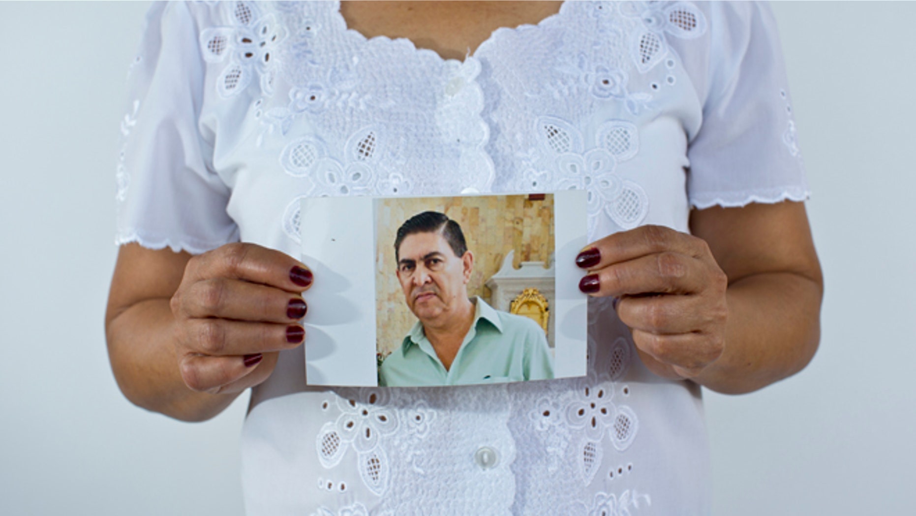 In this June 2, 2015 photo, Yolanda Alvarez Antúnez holds up an image of her husband, Luis Alberto Ramiíez Castillo, in Iguala, Mexico. Her husband was 54 years old when he was kidnapped by armed men outside of his home on Jan. 10, 2013. While trying to pay for the ransom, Yolanda herself was taken by the kidnappers and had to pay extra to be freed. (AP Photo/Dario Lopez-Mills)