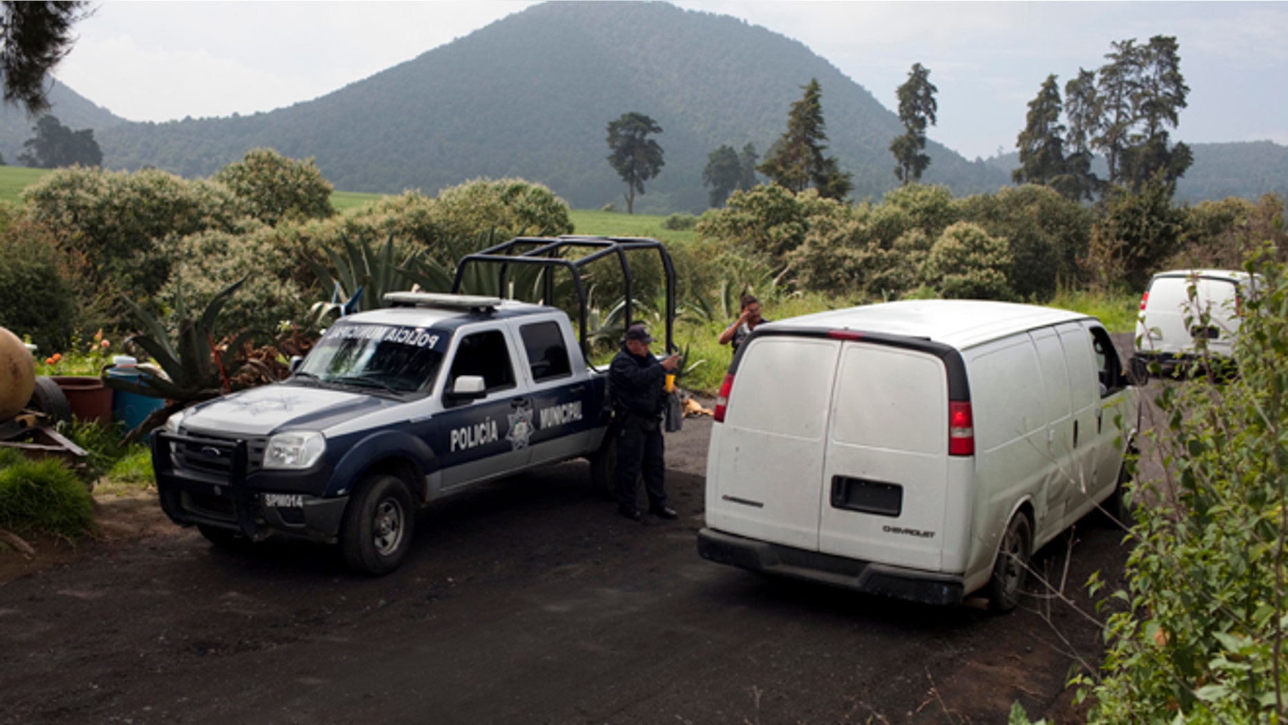 Vans belonging to Mexican authorities arrive at the entrance of a ranch where a mass grave was found in Tlalmanalco, Mexico, Thursday, Aug. 22, 2013. Mexican authorities said Thursday that they have found a mass grave east of Mexico City and are testing to determine if it holds some of the 12 people who vanished from a bar in an upscale area of the capital nearly three months ago. (AP Photo/Ivan Pierre Aguirre)