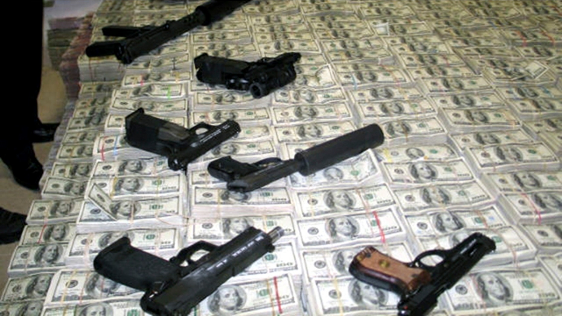 March 15, 2007: A haul of about $206 million is seen with confiscated weapons after the money was found stashed in closets, suitcases, and drawers in a house in an upscale neighborhood of Mexico City.
