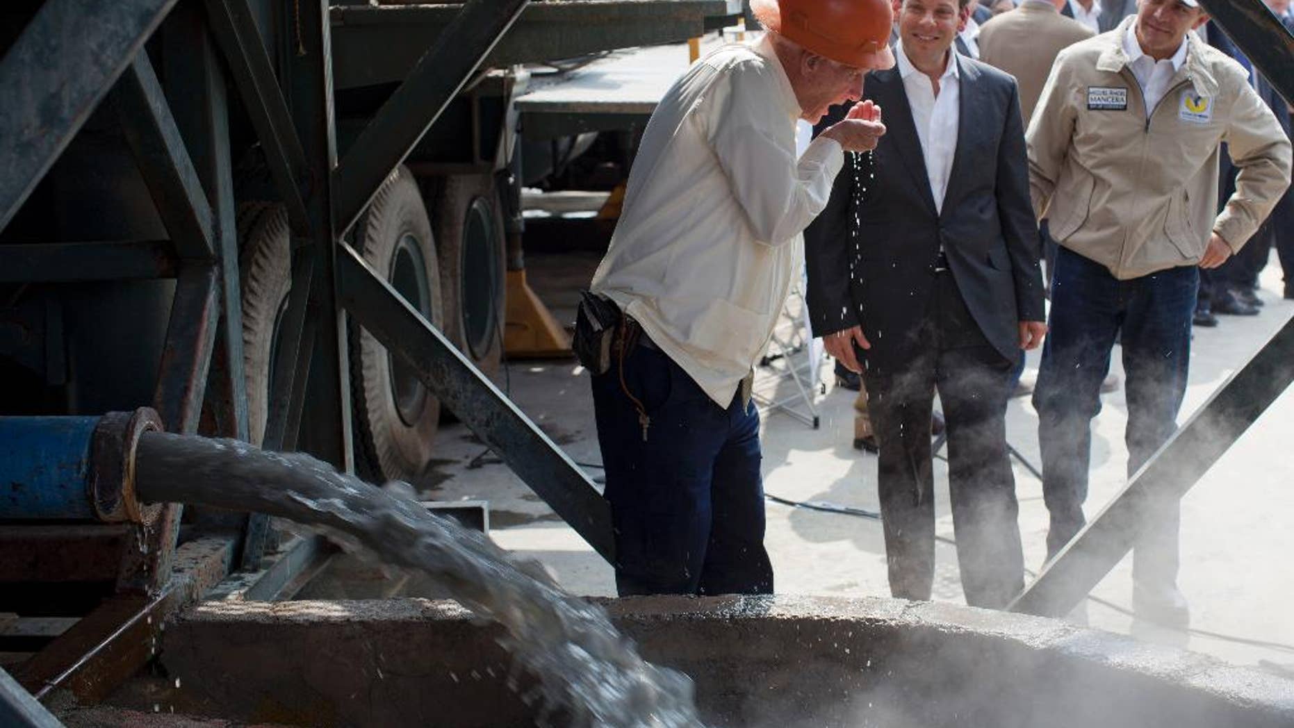 FILE - In this Jan. 23, 2013 file photo, National Water Commission David Korenfeld, center right, watches geologist Federico Mooser take a drink of water from an exploratory well where an aquifer was discovered, in Mexico City. Korenfeld announced his resignation Thursday, April 9, 2015, a week after social media filled with photographs, apparently taken by a neighbor on March 29, showing people walking with suitcases to a helicopter marked with the agency’s name. (AP Photo/Dario Lopez-Mills, File)