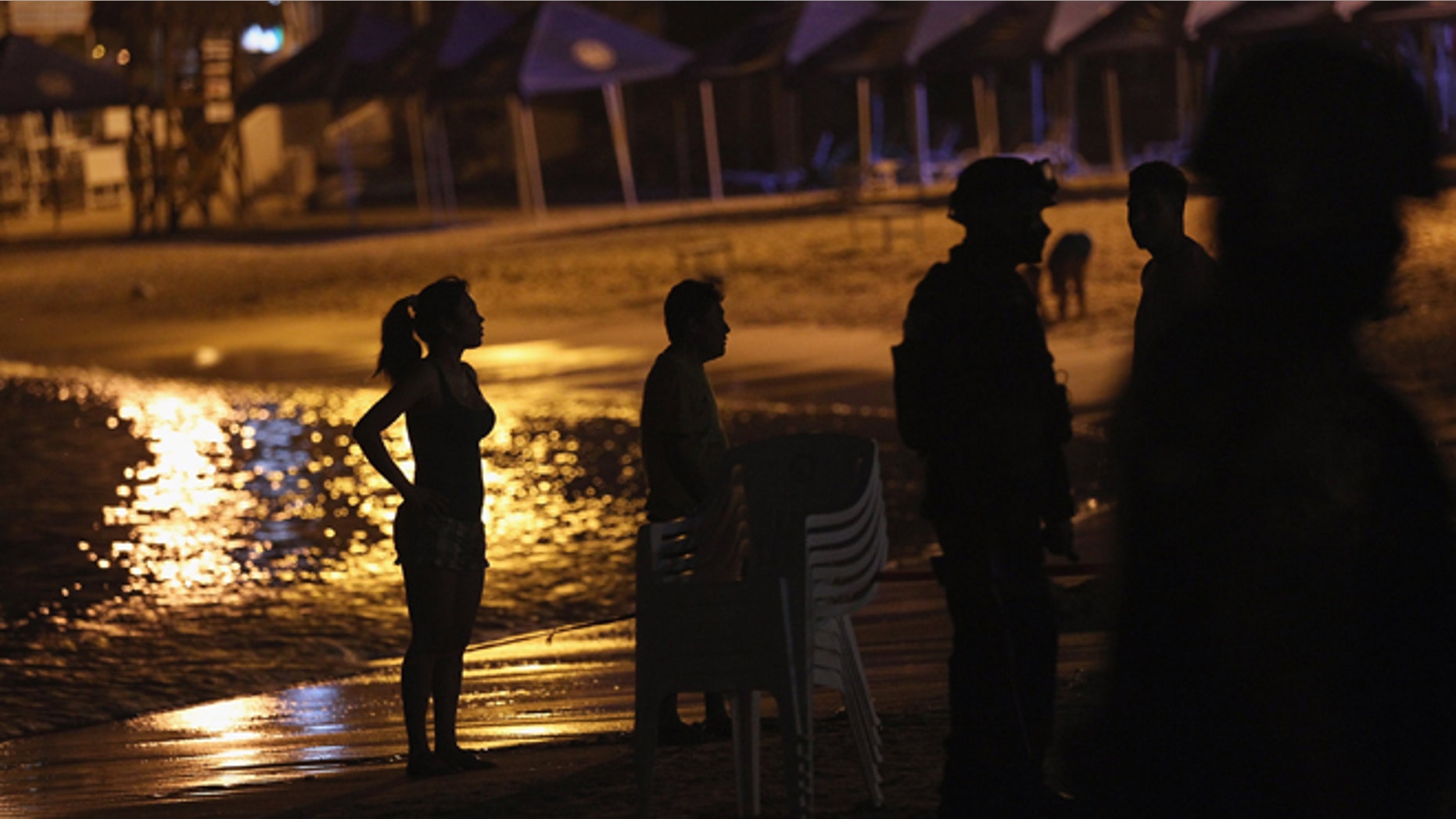 ACAPULCO, MEXICO - MARCH 04: Mexican tourists and soldiers stand look on at the site of a suspected drug-related execution on Acapulco's famous Caleta Beach on March 4, 2012 in Acapulco, Mexico. Drug violence has surged in the coastal resort in the last year, making Acapulco the second most deadly city in Mexico after Juarez. One of Mexico's top tourist destinations, Acapulco has suffered a drop in business, especially from foreign tourists, due to the violence. Toursim accounts for about 70 percent of the economy of Acapulco's state of Guerrero and 9 percent of Mexico's economy. (Photo by John Moore/Getty Images)