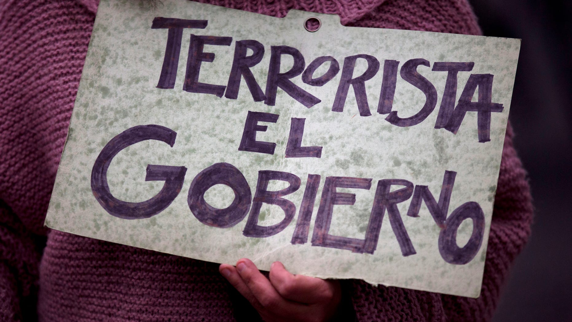 A Protestor holds a sign that reads in Spanish "The Government is terrorist," during a march to call for the return of 43 missing students, as well as the release of 11 people detained during a massive demonstration days earlier, in Mexico City, Tuesday, Nov. 25, 2014. Nearly two months after the students disappeared following an attack by police, protests only continue to multiply, as citizens demand that the government find the missing students alive. (AP Photo/Rebecca Blackwell)