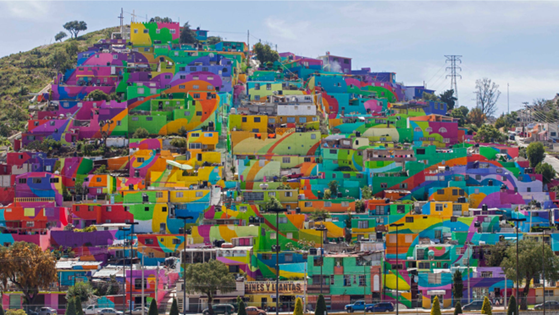 Hundreds of houses painted in bright colors in what organizers claim is Mexico's largest mural, is part of a government-sponsored project is called Pachuca Paints Itself, in the Palmitas neighborhood, in Pachuca, Mexico, Thursday, July 30, 2015. German Crew is the artist collective responsible for painting the mural project. Director Enrique Gomez, who goes by MYBE, said the crew has painted 1,500 square meters with 20,000 liters of paint. The project aims to bring the community together and rehabilitate the area. (AP Photo/Sofia Jaramillo)