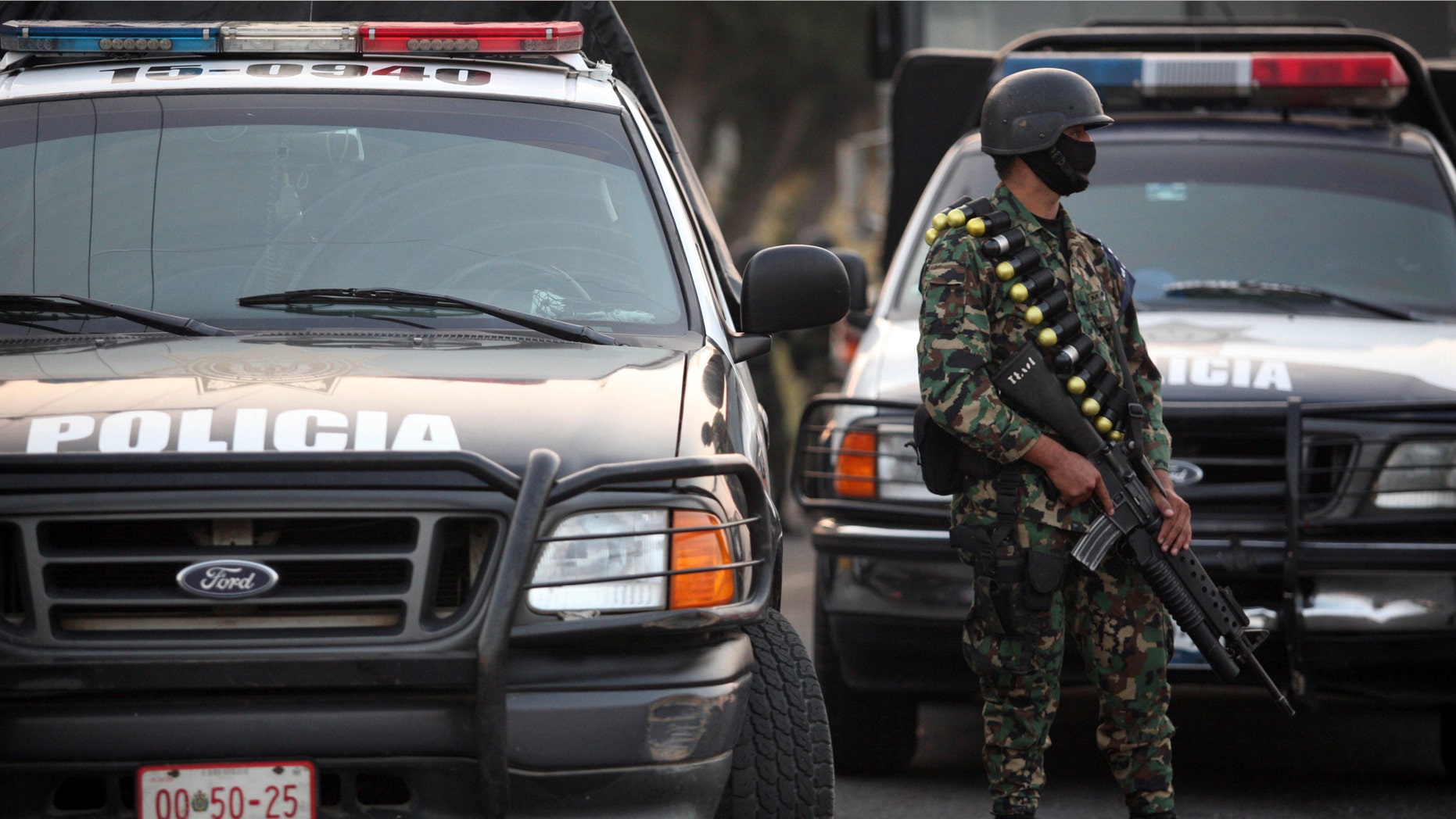 A masked Mexican navy marine keeps custody of police vehicles outside of a police station after the entire police force was disbanded in the Gulf port city of Veracruz, Mexico Wednesday Dec. 21, 2011. The Veracruz state government said the decision is part of an effort to root out police corruption and start from zero in the state's largest city. The navy will be in charge of patrolling the city for the time being. (AP Photo/Felix Marquez)