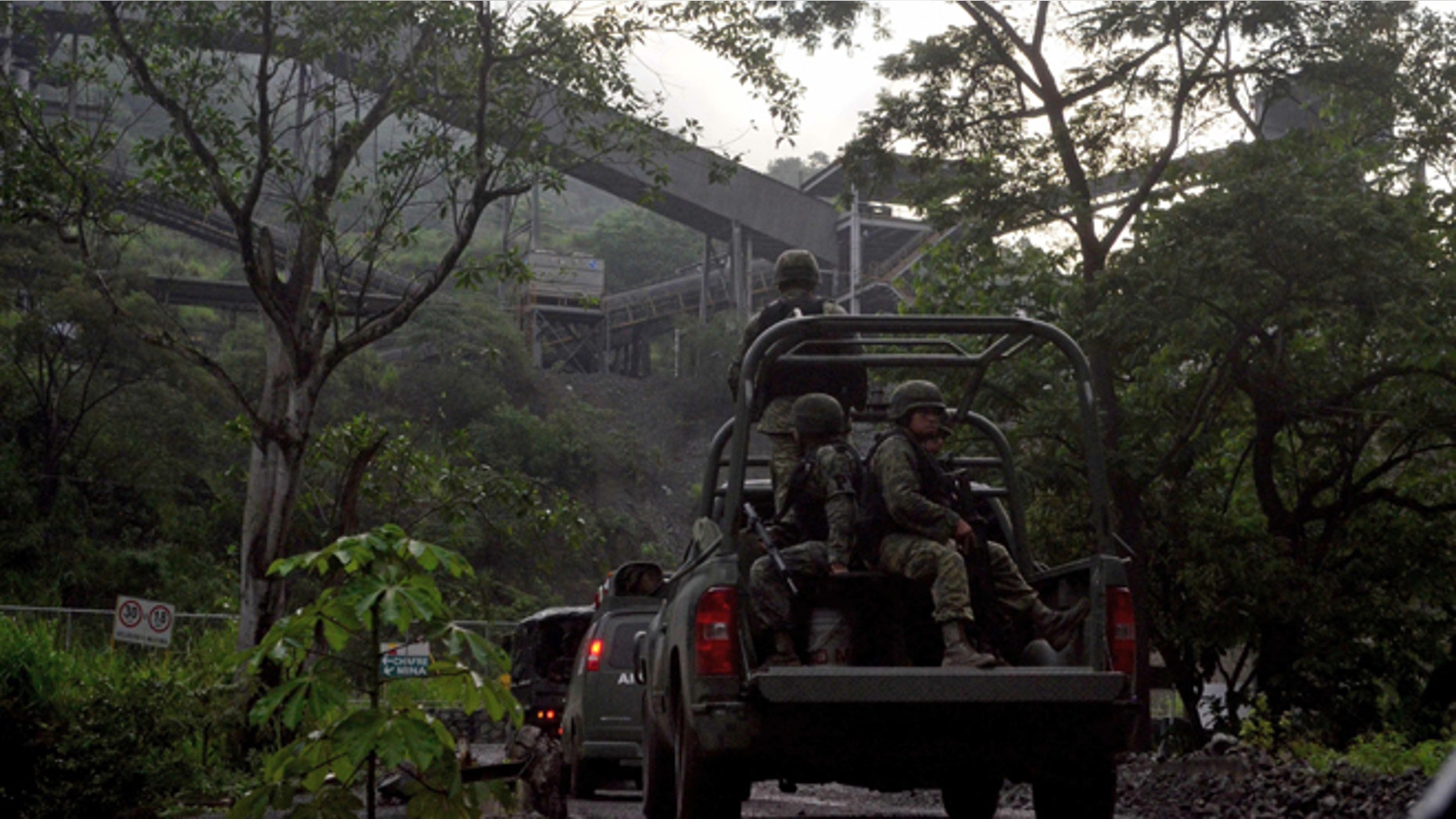 In this Aug. 14, 2013 photo, Mexican army soldiers enter the iron ore mine in the town of Aquila, Mexico. A resident of Aquila, said that since 2012, the Knights Templar cartel demanded residents hand over part of the royalty payments from the local iron ore mine operated by Ternium, a Luxembourg-based consortium. Mexican drug cartels long ago moved into oil theft, pirated goods, extortion and kidnapping, but it still came as a shock this month when federal officials revealed the gangs have broadened the scope and sophistication of their economic empires by entering the countryâs lucrative mining industry, exporting iron ore to Chinese and other foreign mills. (AP Photo/Agencia Esquema)