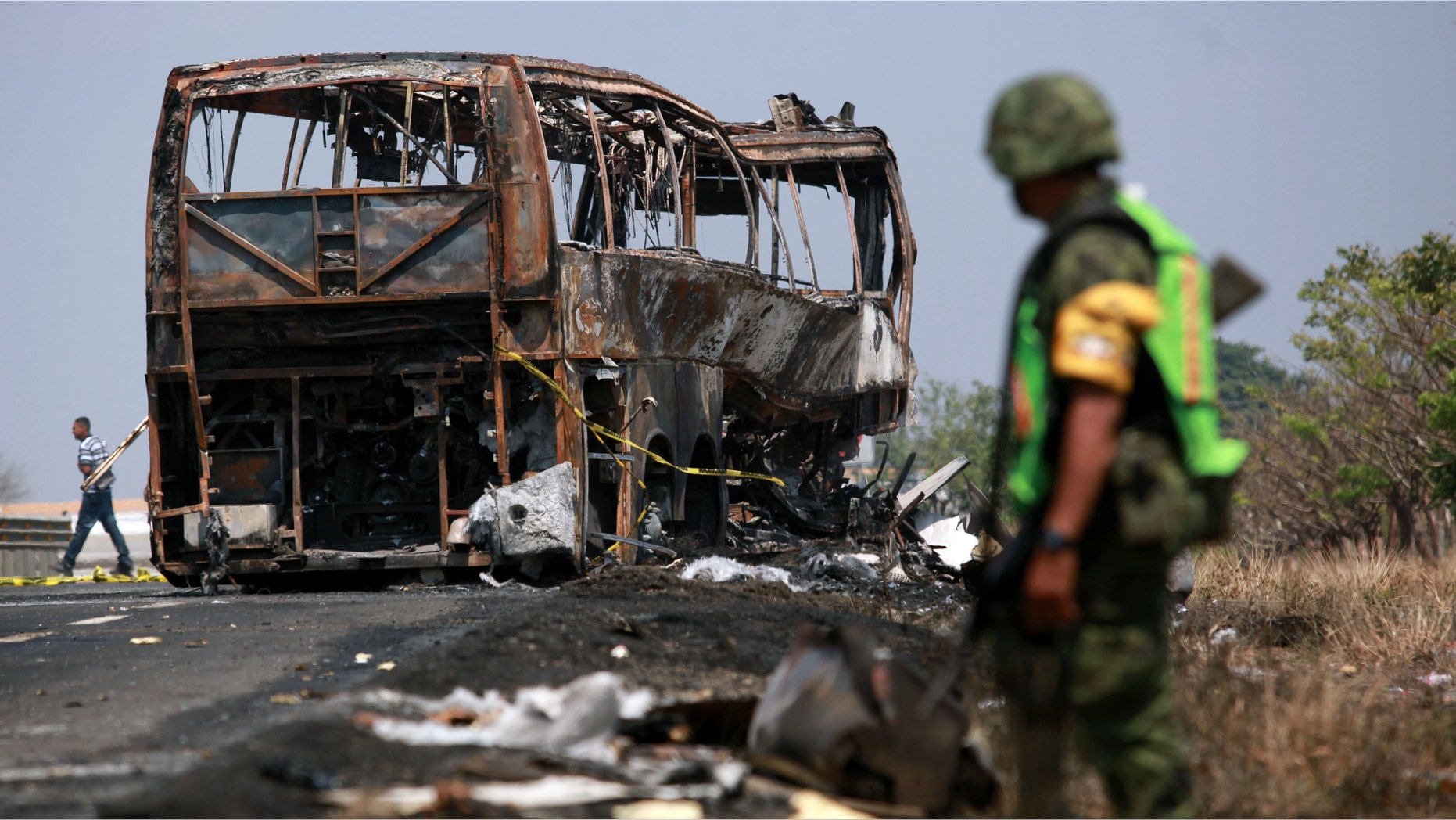 A soldier guards the site where a passenger bus slammed into a broken-down truck and burst into flames near the town of Ciudad Isla in the Gulf state of Veracruz, Mexico, Sunday, April 13, 2014. Dozens of people traveling on the bus to Mexico City burned to death inside the bus. (AP Photo/Felix Marquez)
