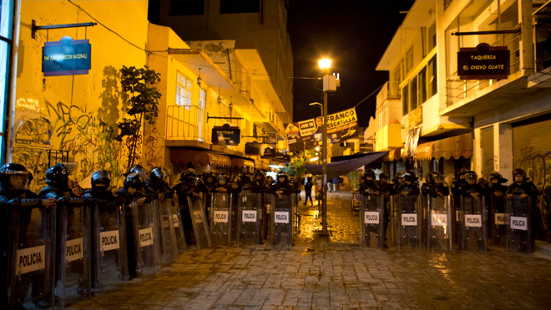 Police stand guard in the pedestrian street where a small explosive was tossed at National Action Party headquarters, in Chilpancingo, Mexico, in the early morning hours of Friday, June 5, 2015. Radical groups and unionized teachers have vowed to block Sunday's voting for the lower house of congress, nine governorships and hundreds of mayorships. (AP Photo/Rebecca Blackwell)