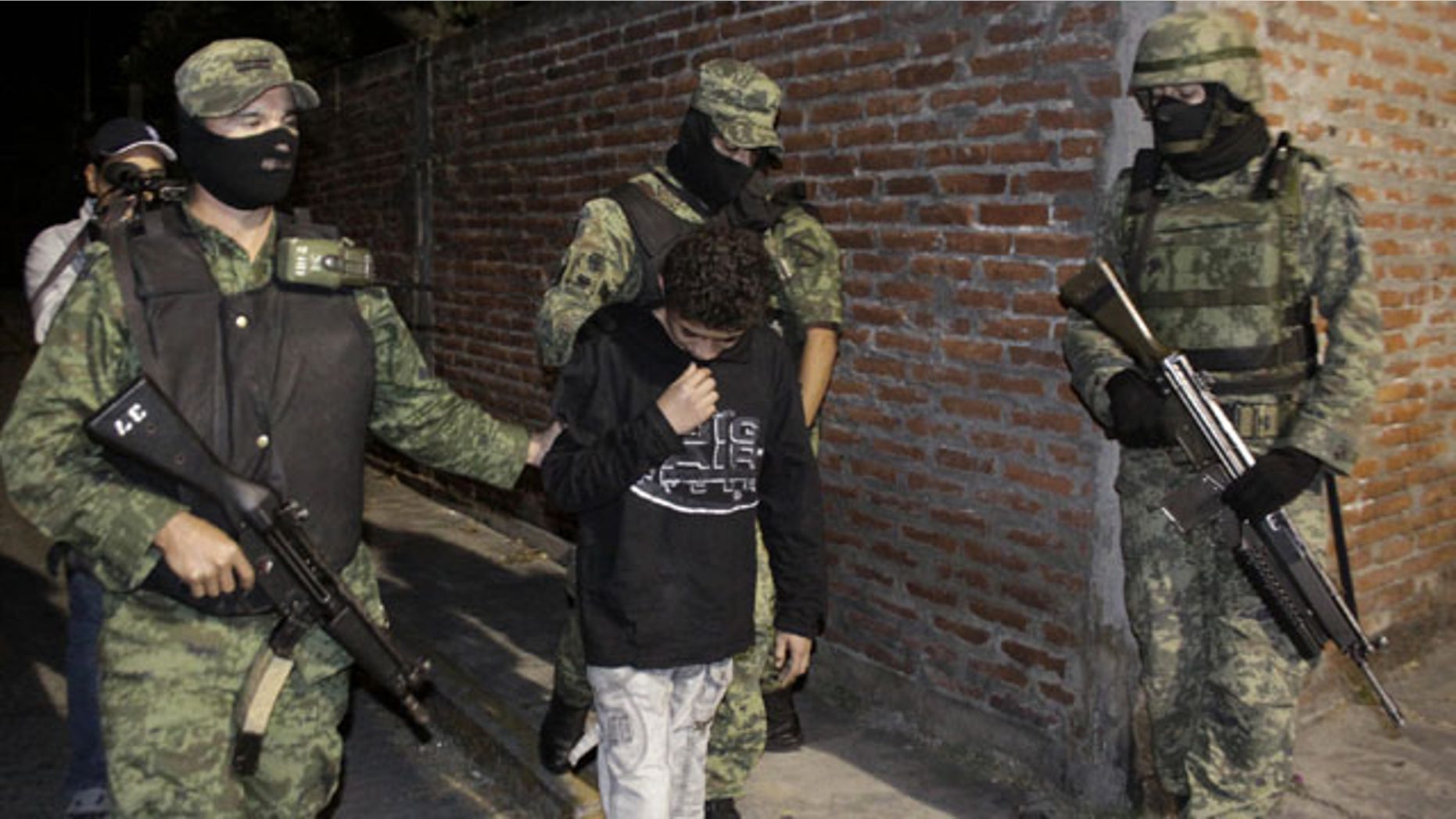 FILE - In this Dec. 3, 2010 file photo, Mexican soldiers present Edgar "El Ponchis" Jimenez Lugo to the media in the city of Cuernavaca, Mexico. The teenage U.S. citizen who acknowledged being a drug-cartel killer has finished his three year juvenile-offender term for homicide, kidnapping and drug and weapons possession. (AP Photo)