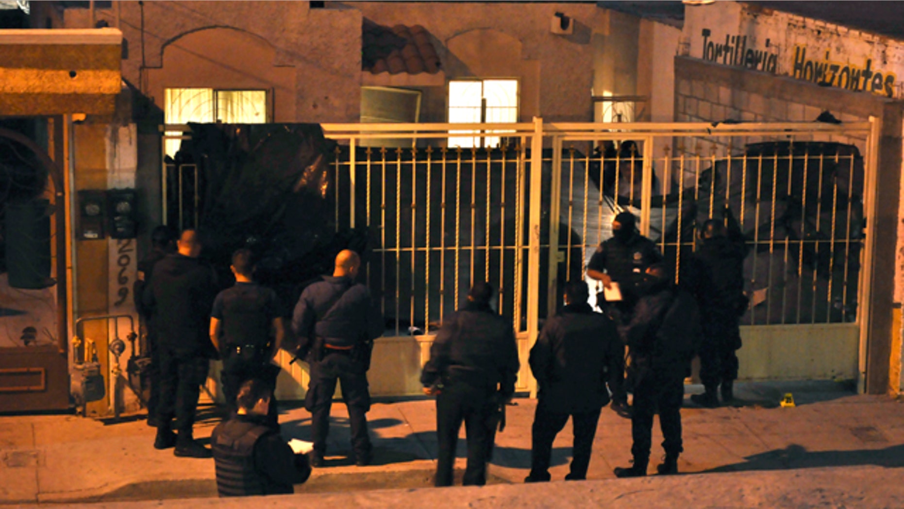 Oct. 22, 2010: Mexican federal police officers stand outside a home after the exterior gate was covered with a plastic tarp in the northern city of Ciudad Juarez, Mexico. At least 13 people were shot dead and 15 wounded in an attack on this house during a party in Ciudad Juarez, the second such massacre in less than a week in the violent border city.