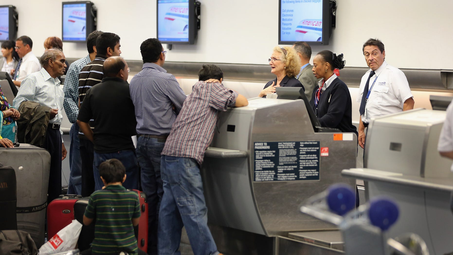 MIAMI, FL - APRIL 16: American Airlines passenger are helped at the ticket counter at Miami International Airport on April 16, 2013 in Miami, Florida. Thousands of American Airlines travelers became stranded today when the airline was forced to ground all its flights after a nationwide problem with its computer systems (Photo by Joe Raedle/Getty Images)