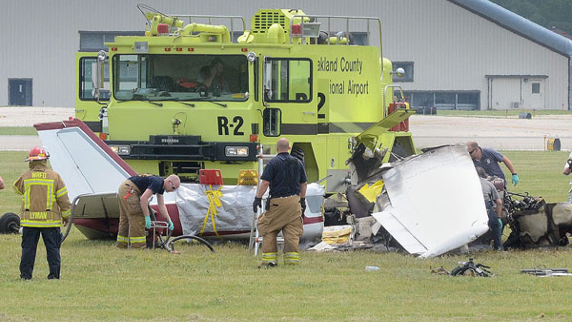 June 21, 2013: Emergency personnel looks over the scene of a plane crash at Oakland International Airport in Waterford, Mich. A pilot and three passengers have were killed after a small plane crashed shortly after takeoff from the airport northwest of Detroit.