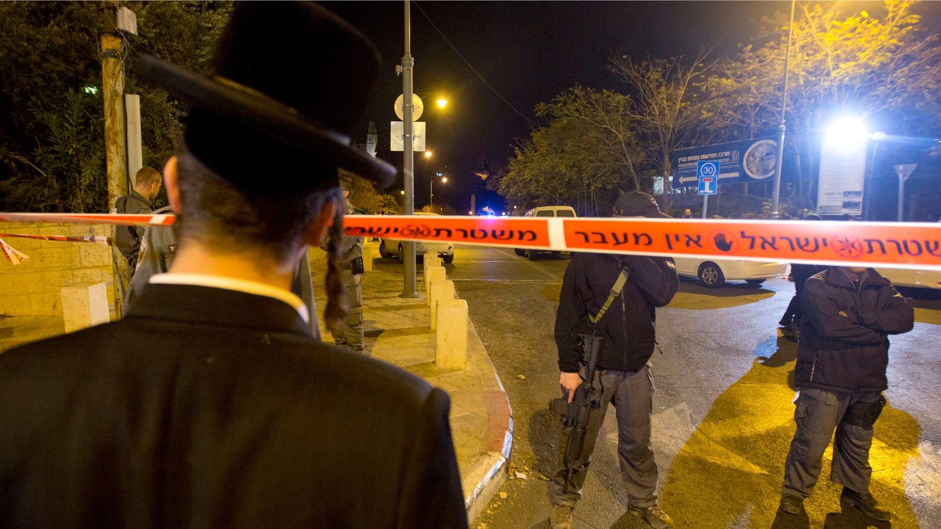 Oct 29, 2014: An ultra-Orthodox Jewish man looks as Israeli police officers stand guard at the scene of a shooting in Jerusalem