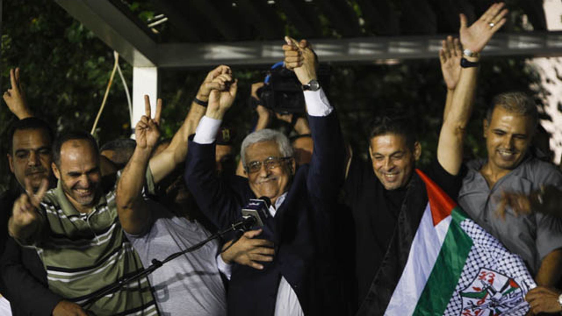 August 14, 2013: Palestinian President Mahmoud Abbas, center, waves with released Palestinian prisoners at his headquarters in the West Bank city of Ramallah. Israel released 26 Palestinian inmates, including many convicted in grisly killings, on the eve of long-stalled Mideast peace talks, angering families of those slain by the prisoners, who were welcomed as heroes in the West Bank and Gaza. (AP Photo)