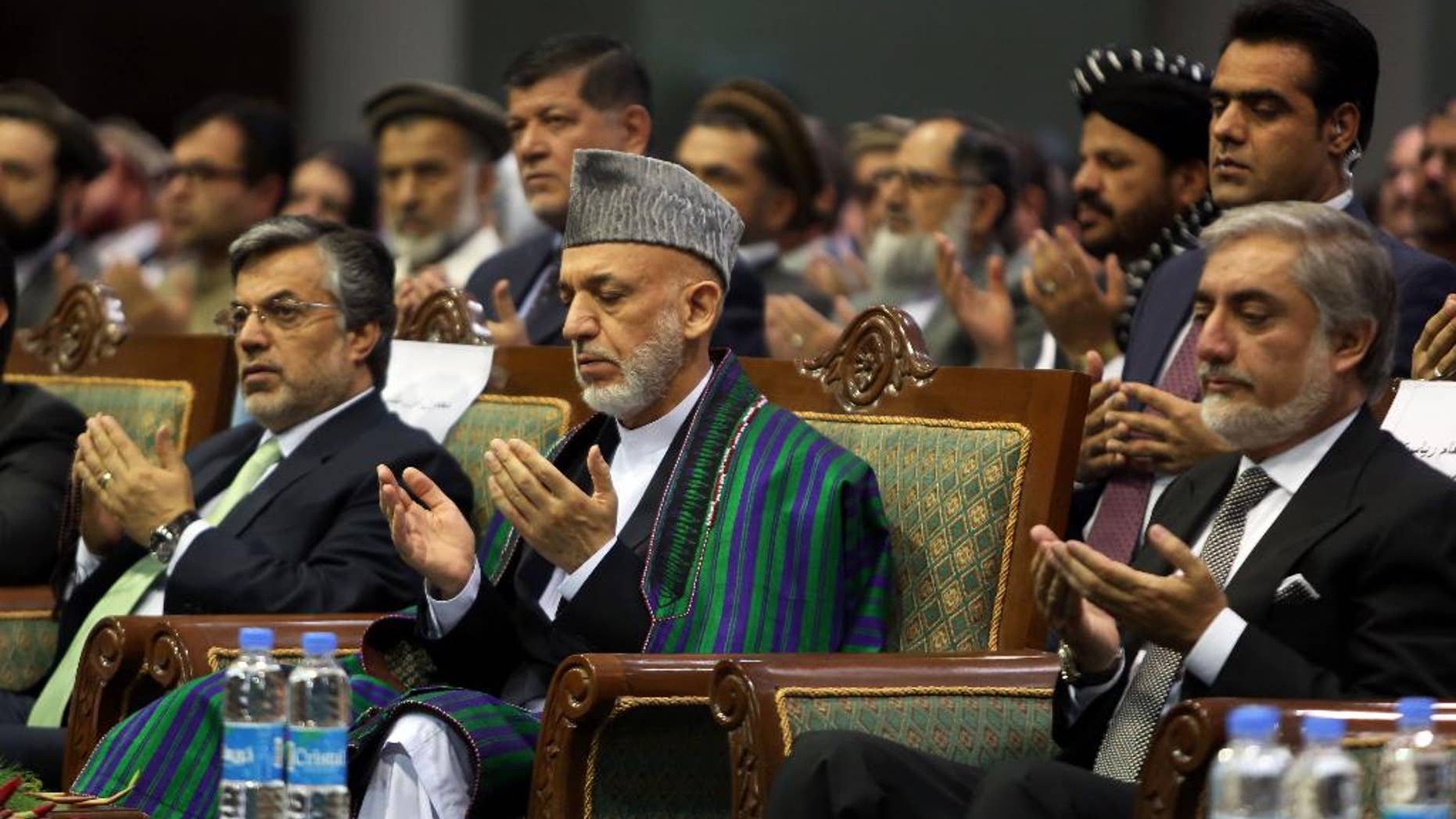 Afghan President Hamid Karzai, center, and Afghan presidential candidate Abdullah Abdullah pray during a ceremony marking the third anniversary of the assassination of former Afghan President Burhanuddin Rabbani in Kabul, Afghanistan, Saturday, Sept. 20, 2014. In 2011, an insurgent with a bomb wrapped in his turban assassinated Rabbani, who was leading a government effort to broker peace with the Taliban. (AP Photo/Rahmat Gul)