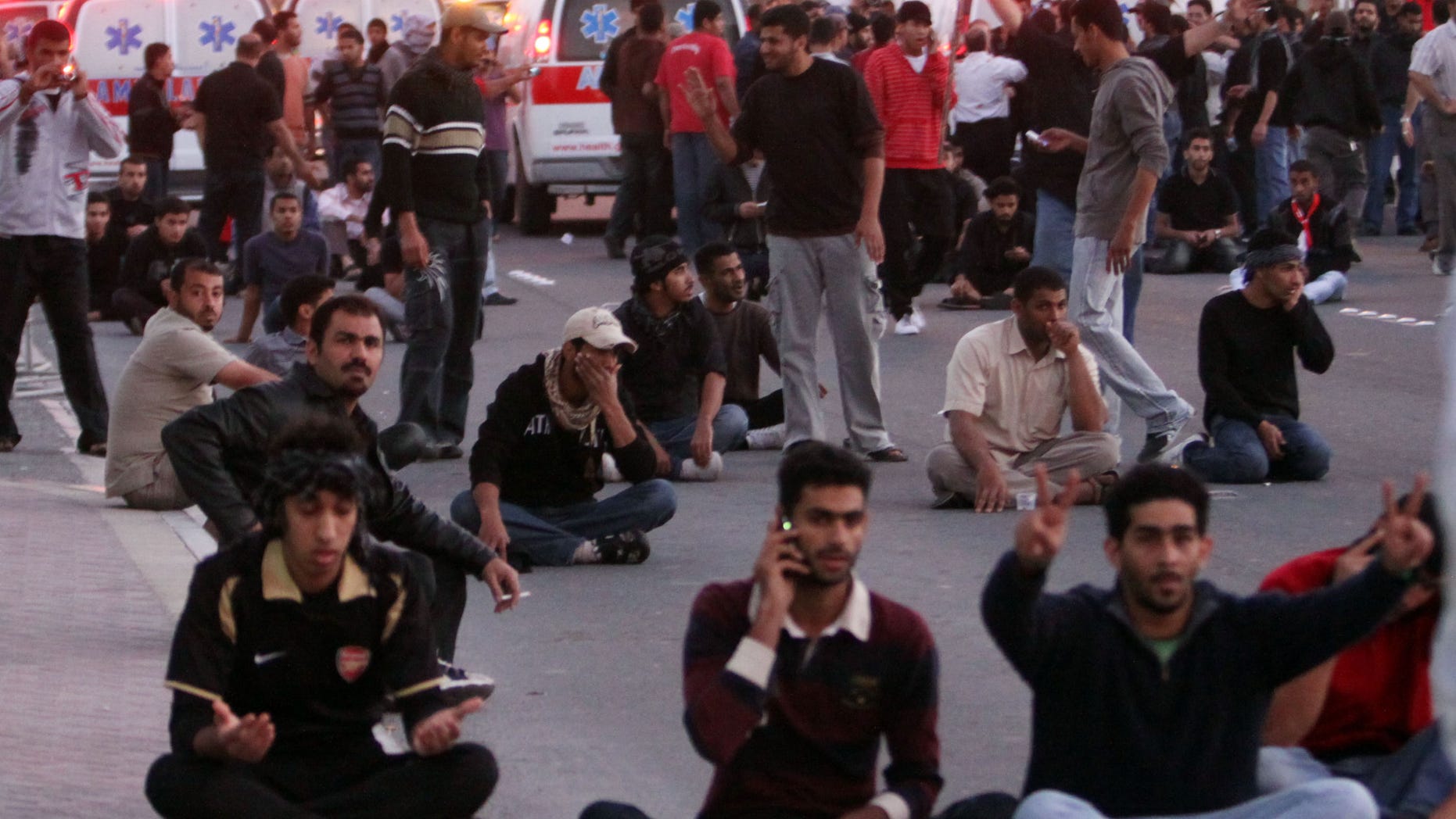 Bahraini protesters pray and sit in the street facing army tanks, unseen, while ambulances behind them take wounded demonstrators to hospital after clashes near the Pearl roundabout Friday, Feb. 18, 2011, in Manama, Bahrain. Soldiers fired tear gas and shot heavy weapons into the air as thousands of protest marchers defied a government ban and streamed toward the landmark square that had been the symbolic center of the uprising against the Gulf nation's leaders.