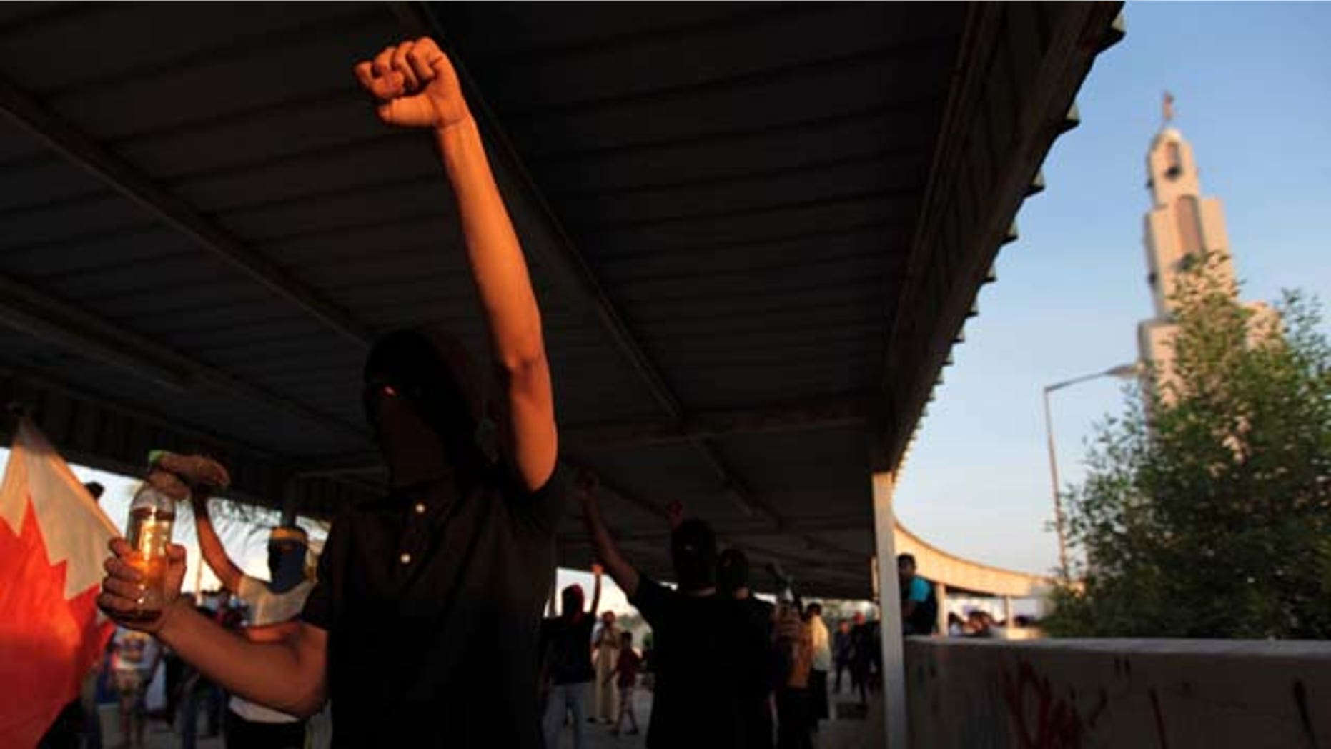August 10, 2013: Masked Bahraini anti-government protesters carrying petrol bombs and national flags chant slogans as they prepare for clashes with riot police. (AP Photo)