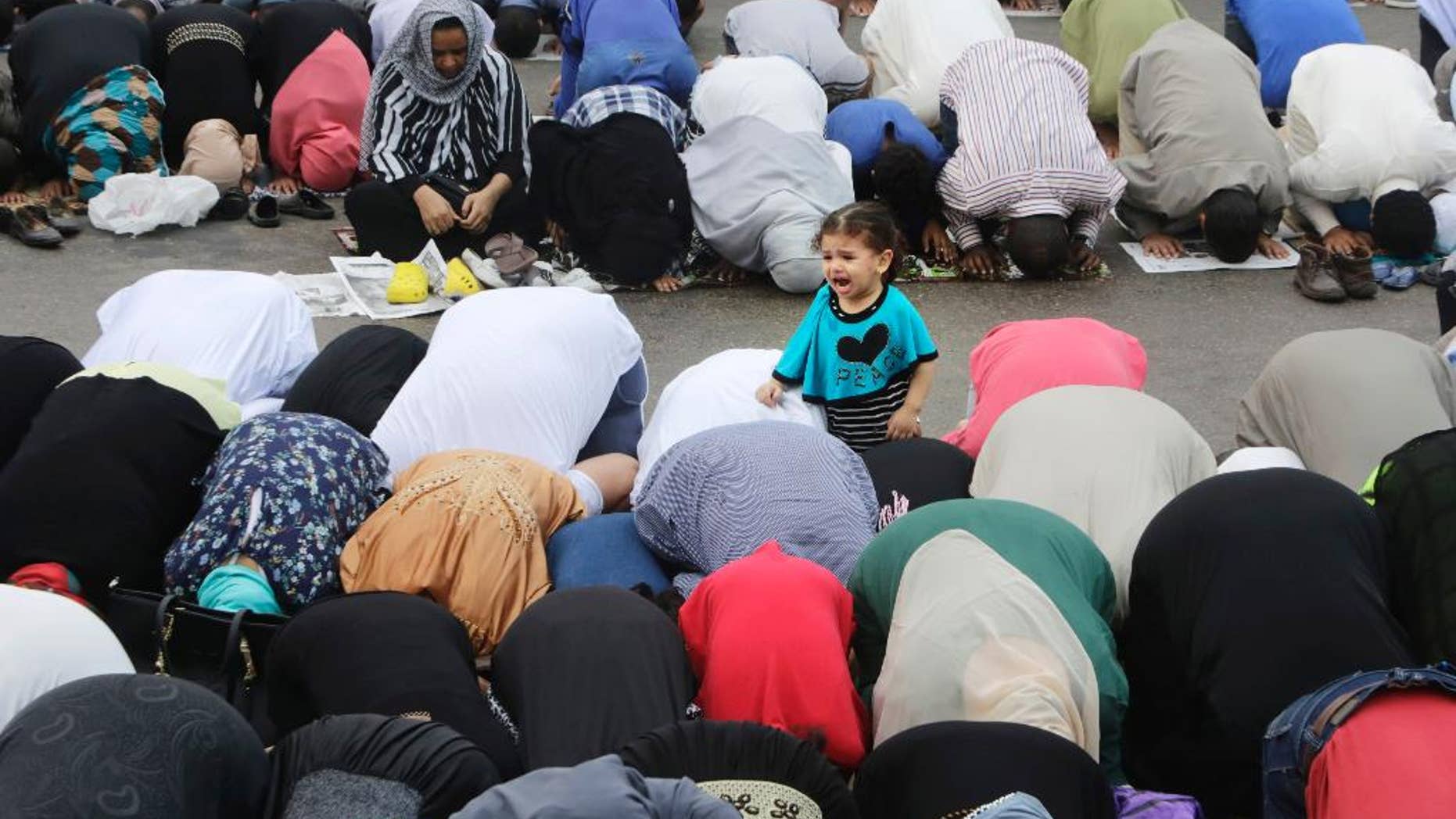 An Egyptian girl cries as her mother joins others offering an Eid al-Fitr prayer, marking the end of the Muslim holy month of Ramadan in Cairo, Egypt, Friday, July 17, 2015. (AP Photo/Amr Nabil)
