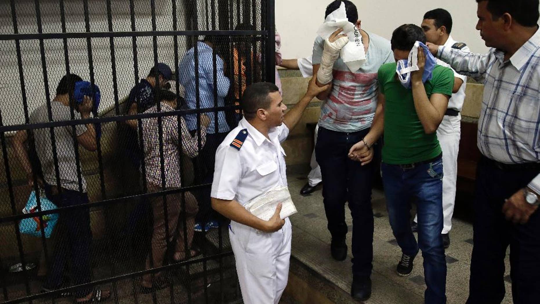 FILE - In this Saturday, Nov. 1, 2014 file photo, Eight Egyptian men convicted for "inciting debauchery" following their appearance in a video of an alleged same-sex wedding party on a Nile boat leave the defendant's cage in a courtroom in Cairo, Egypt. An Egyptian official says security forces raided a bath house and arrested 25 men for homosexuality, dragging them naked out of the building in downtown Cairo. (AP Photo/Hassan Ammar, File)