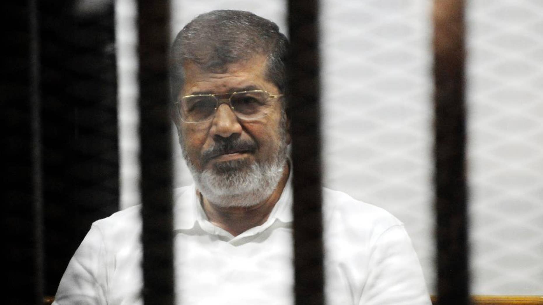 FILE - In this file photo taken Monday, Nov. 3, 2014, Egypt's ousted Islamist President Mohammed Morsi sits in the defendant cage in the Police Academy courthouse during a court hearing on charges of inciting the murder of his opponents, in Cairo, Egypt. Egypt's state news agency said prosecutors have asked for the death sentence for Morsi and other Muslim Brotherhood leaders on trial on espionage charges. (AP Photo/Mohammed al-Law, File)