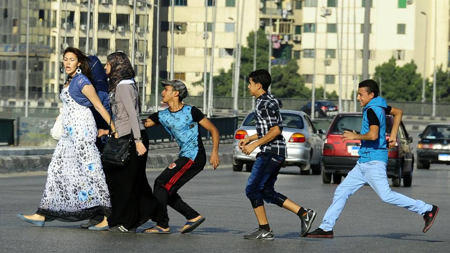 FILE -- In this Monday, Aug. 20, 2012 file photo, an Egyptian youth, trailed by his friends, gropes a woman crossing the street with her friends in Cairo, Egypt. Abdel-Fattah el-Sissi, Egypt's newly sworn-in president, has apologized in person to a woman who was sexually assaulted by a mob during weekend celebrations marking his inauguration. Several women were assaulted during the Sunday, June 8, 2014 inaugural festivities. (AP Photo/Ahmed Abd El Latif, El Shorouk Newspaper, File) EGYPT OUT