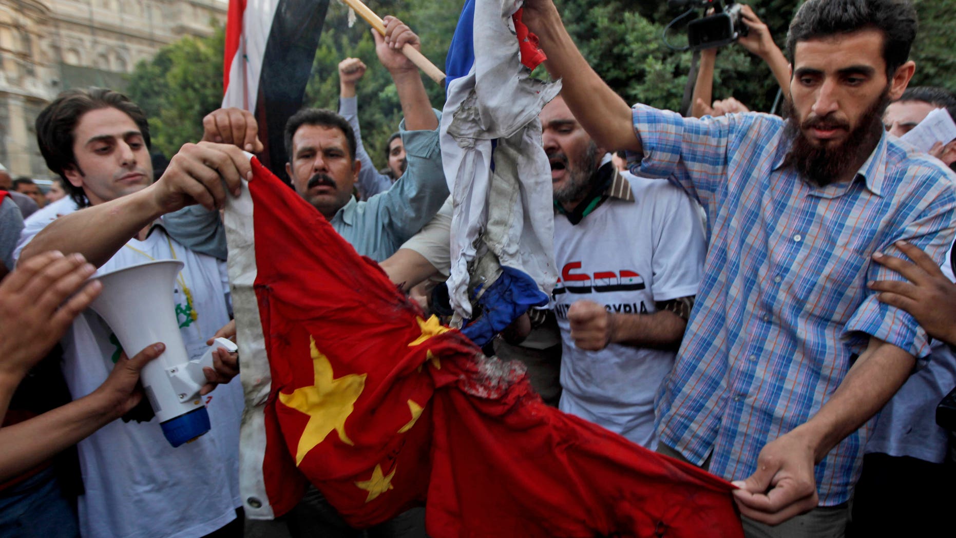 Syrian protesters burn the national flags of China and Russia during an anti-Syrian regime protest in front of the Arab league headquarters in Cairo, Egypt Sunday, Oct. 16, 2011.