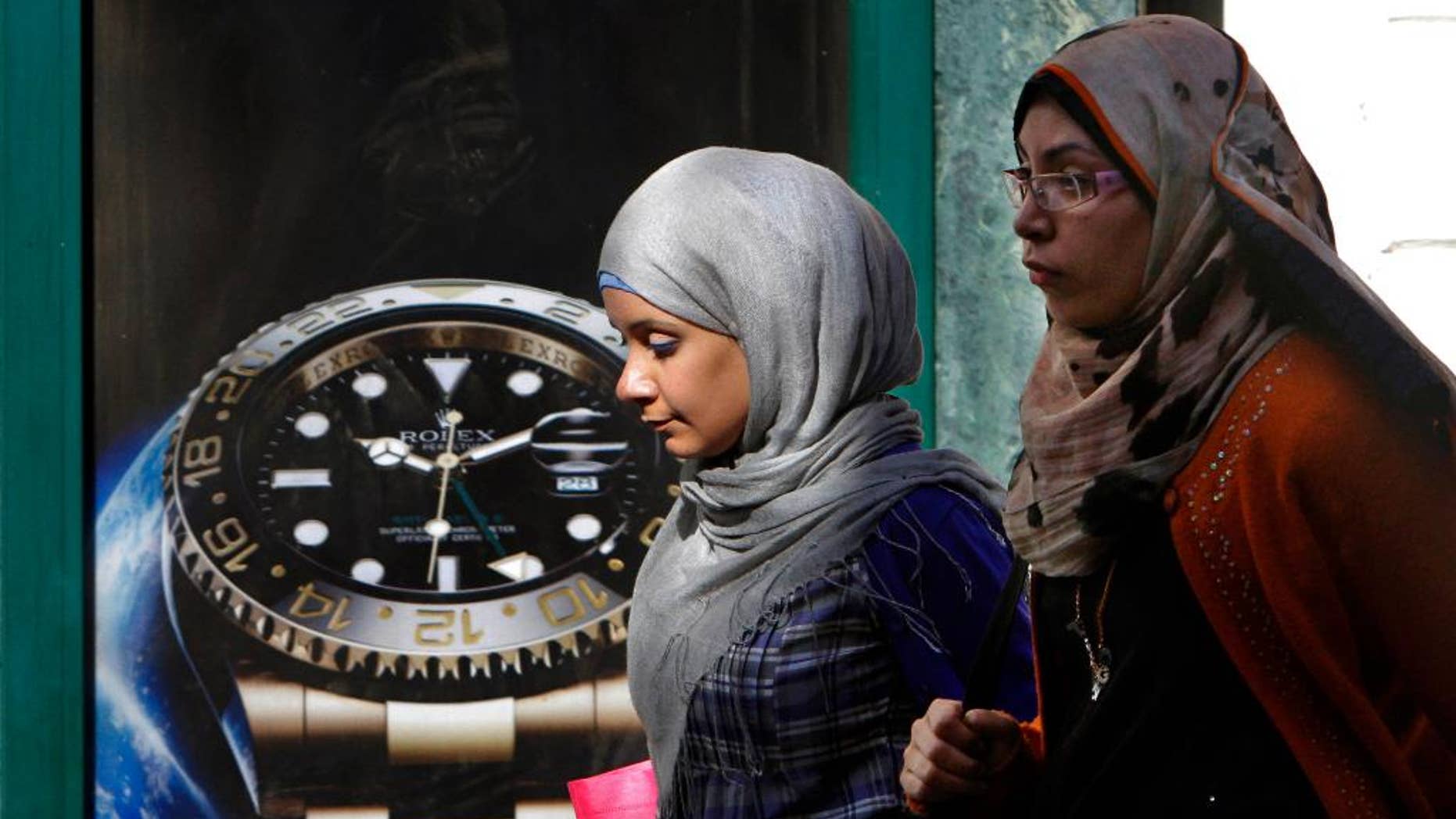 FILE - In this Monday, March 25, 2013 file photo, Egyptians walk in front of an advertisement for a watch in Cairo, Egypt. On midnight Thursday, Sept. 25, 2014, Egypt rolled back clocks one hour for the end of daylight savings time in the fourth time change in less than five months. Egypt is now two hours ahead of Greenwich Mean Time. In May the government moved clocks ahead one hour as a power-saving measure. It then switched clocks for the start and end of Ramadan, the Muslim fasting month, which this year fell in the scorching months of June and July. (AP Photo/Amr Nabil, File)