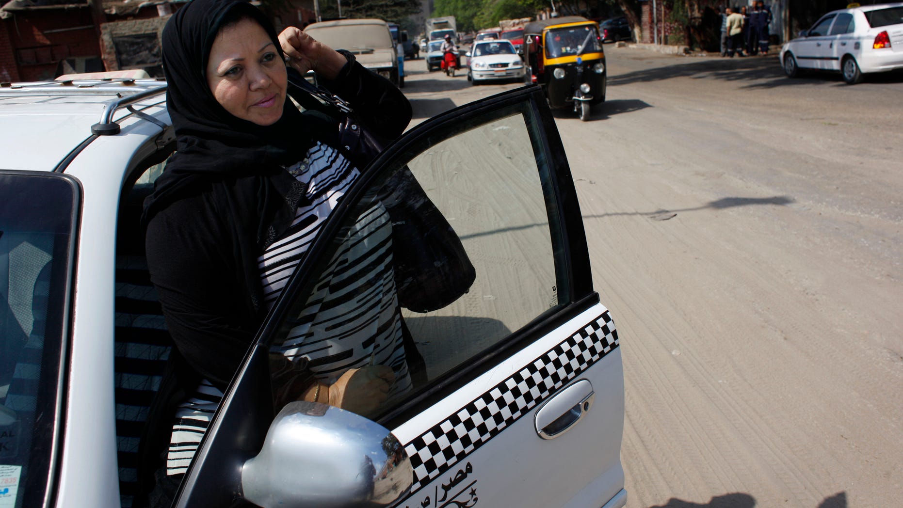Oct. 3, 2011: Egyptian woman taxi driver Nadia Abdel-Gaber exits her taxi to take a break during her work day in Cairo, Egypt. Abdel-Gaber frequently gets double-takes from customers who hail her cab. Driving a cab is considered a man's work in conservative Egypt.
