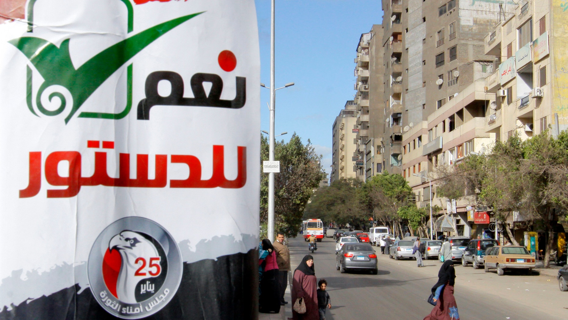 Dec. 21, 2012 - Egyptians walk near an Arabic poster reading "yes to the constitution" in Giza, Egypt.