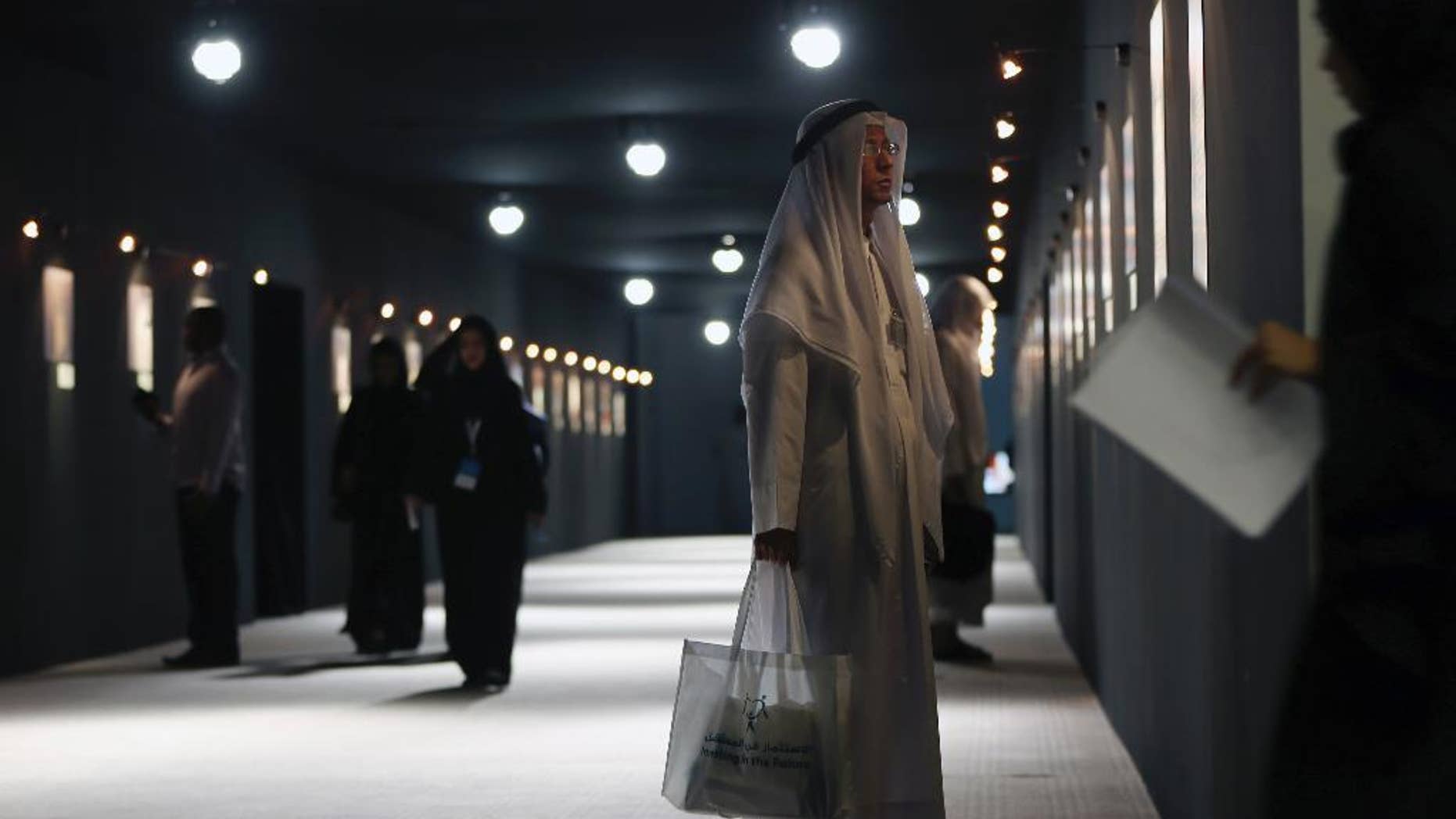 An Emirati visitor watches a photo exhibition titled "Do you see what I see" about refugee children at the "Investing in the future, protecting refugee children and adolescents - Mena" conference organized by UNHCR at Al Jawaher Reception and Convention Centre in Sharjah, United Arab Emirates, Wednesday, Oct. 15, 2014. The head of the United Nations refugee agency is urging countries, particularly in Europe, to open up more to Syrians fleeing their country's civil war. (AP Photo/Kamran Jebreili)