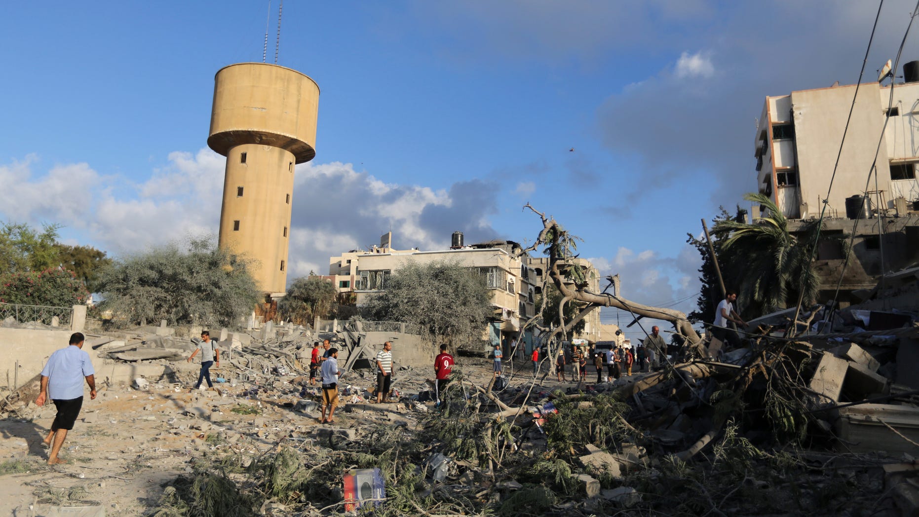July 25, 2014 - Palestinians walk on the rubble of buildings damaged in an Israeli airstrike in Gaza City,