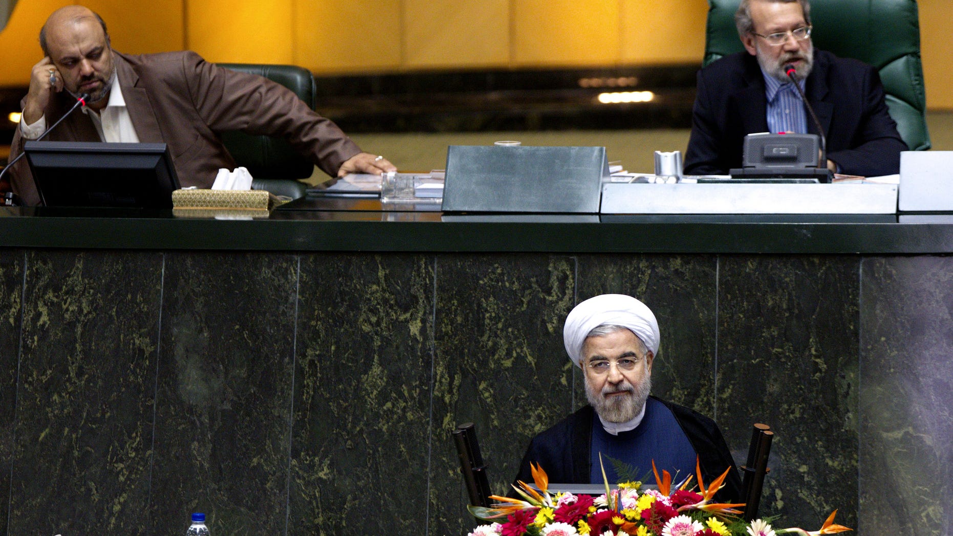Iranian President Hasan Rouhani, bottom, listens during a parliament session to defend the nominees for the three remaining ministries of his cabinet while parliament speaker Ali Larijani speaks, top right, in Tehran, Iran, Sunday, Oct. 27, 2013. Irans parliament has rejected a close ally of Rouhani for a ministerial post. In a vote Sunday, 141 out of 261 lawmakers present voted against Reza Salehi Amiri, who Rouhani nominated as sports and youth minister. (AP Photo)