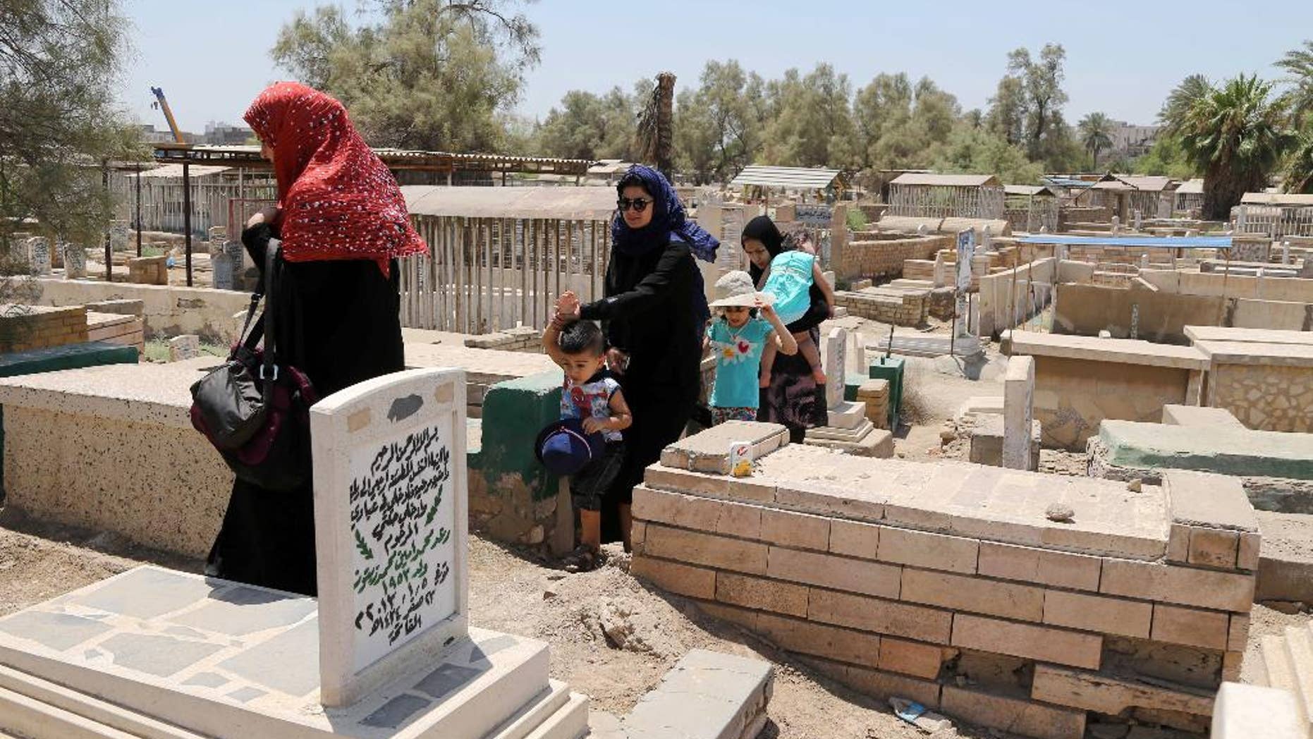 Iraqis visit the grave of a relative on the first day of Eid al-Fitr in Baghdad, Iraq, Monday, July 28, 2014. Monday marked the beginning of the three-day Eid al-Fitr holiday, which caps the Muslim fasting month of Ramadan. Muslims usually start the day by visiting cemeteries, to pay their respects to the dead, and then exchange family visits. (AP Photo/Karim Kadim)