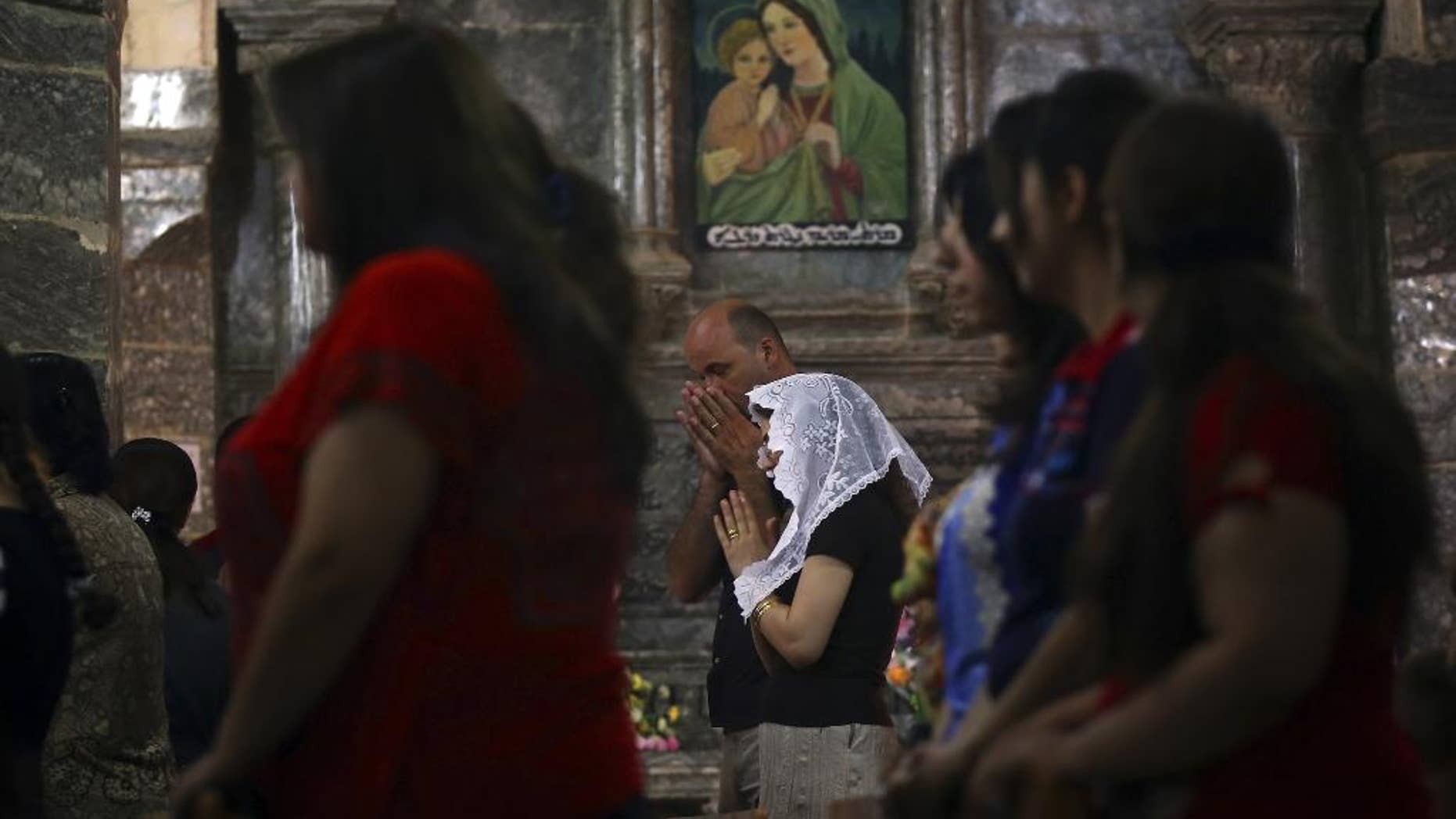 In this Sunday, June 15, 2014 photo, Iraqis attend Mass at the Chaldean Church of the Virgin Mary of the Harvest, in al-Qoush, set in the seventh century Saint Hormoz monastery built into a hill overlooking Alqosh, a village of some 6,000 inhabitants about 50 kilometers (31 miles) north of Mosul, northern Iraq. Dozens of Christian families that fled to this ancient Iraqi village have taken a much-traversed route -- many from their minority community have escaped to Alqosh before, in fear for their lives. This time, few say they want to go back to their homes, seeking safety under the Kurdish forces known as the peshmerga. (AP Photo)