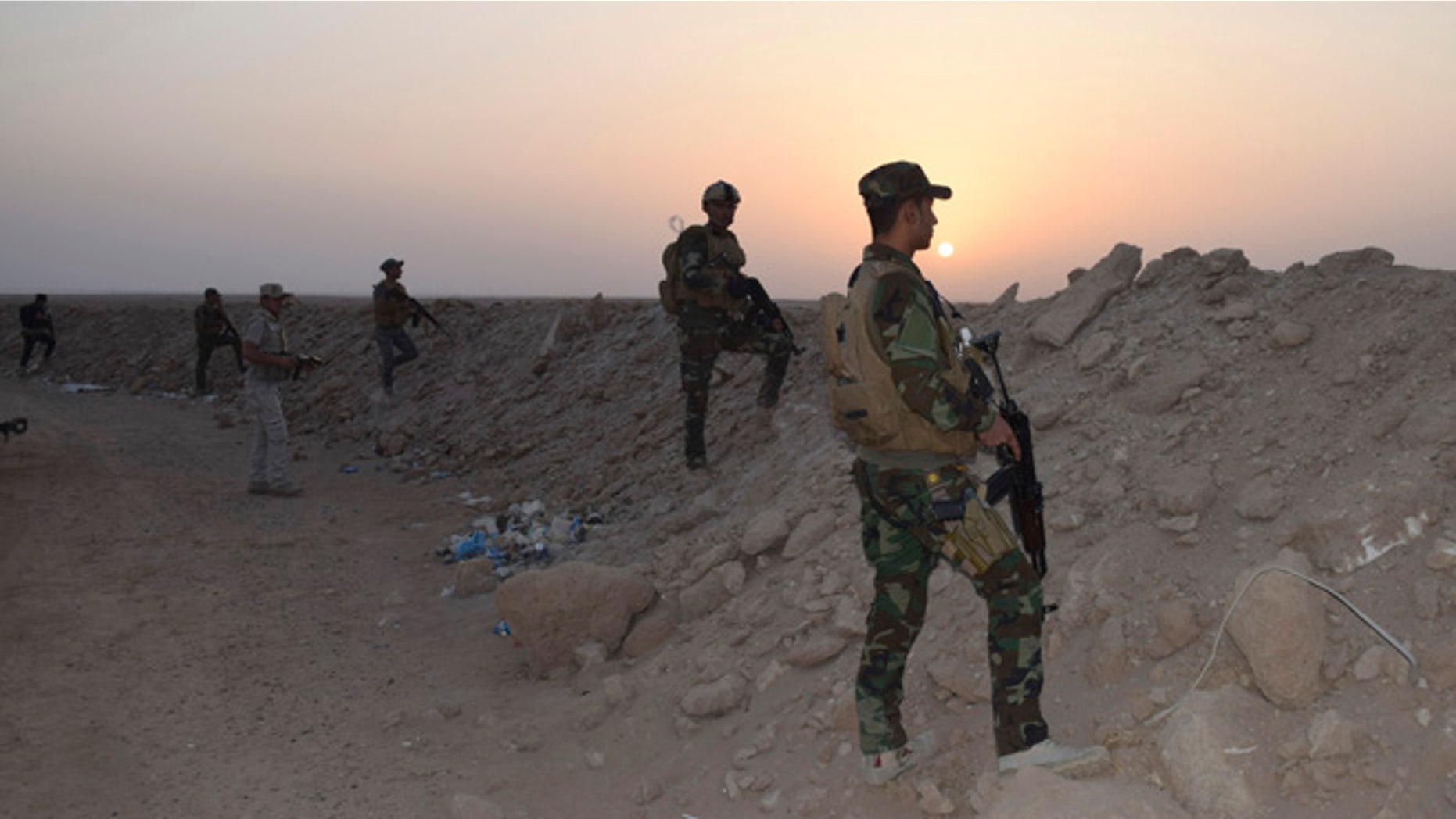 Oct. 15, 2015: Iraqi security forces and Sunni volunteer tribal fighters stand guard as the sun sets after clashes against ISIS.