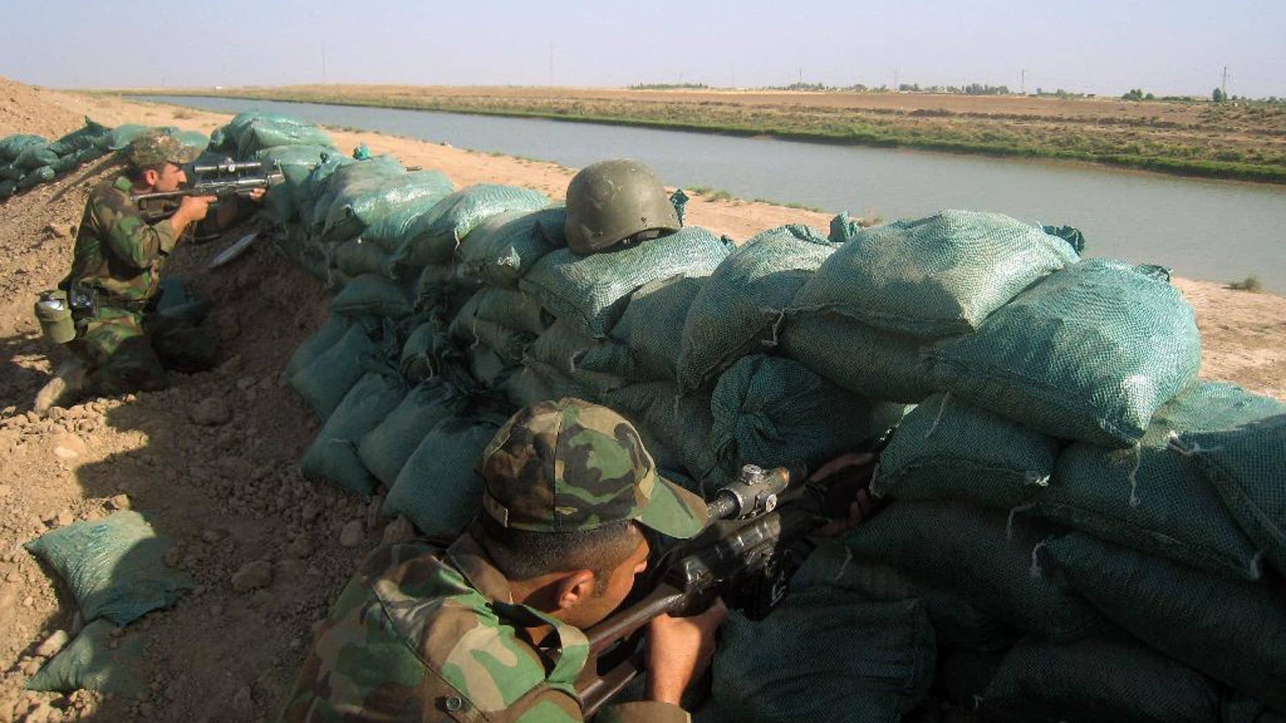 Kurdish security forces take positions at Taza district, south of the oil-rich city of Kirkuk, Iraq, Friday, June 20, 2014. Among rolling wheat fields with machine-gun fire rattling in the distance, Kurdish fighters patrol the new frontier of their autonomous region of northern Iraq, dozens of miles from their official border. In front of them are Islamic militants, behind them is the Kurds' newly captured prize, stretches of oil-rich territory. (AP Photo/ Emad Matti)