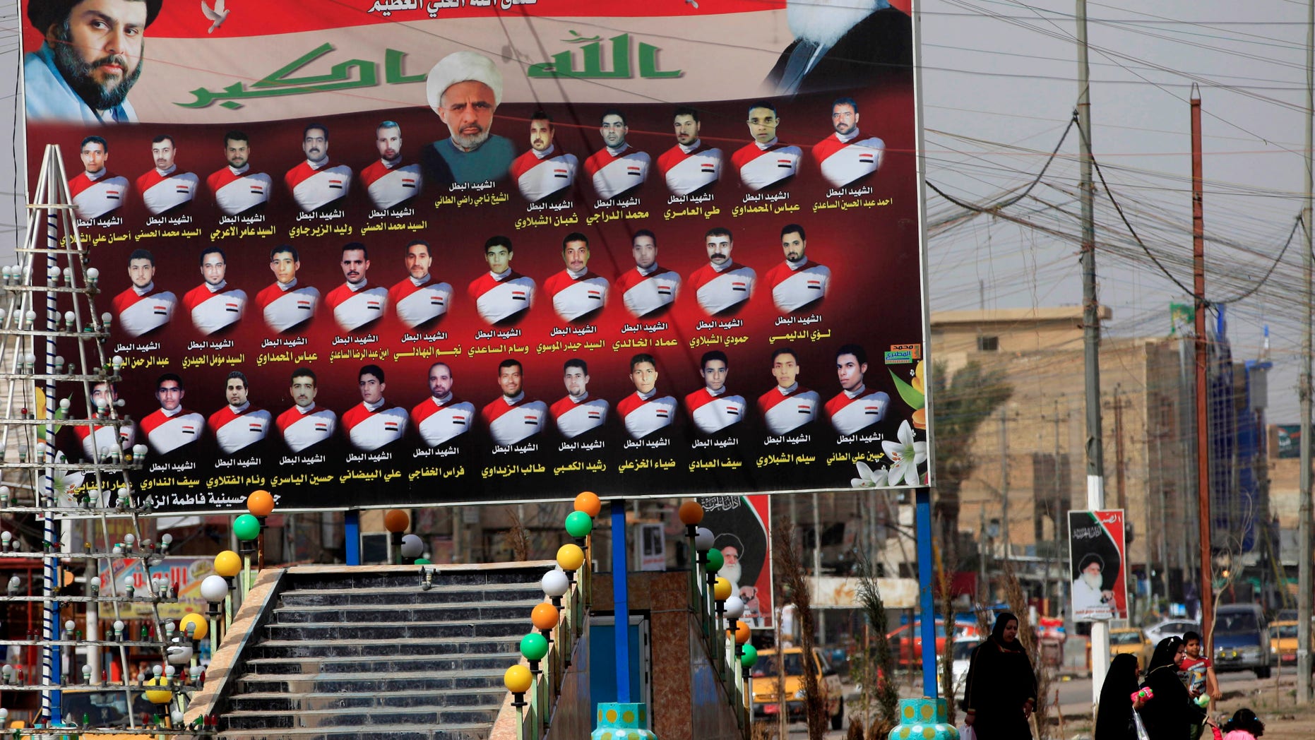 Feb. 24, 2013 - Iraqi women walk past a billboard showing Shiite religious leaders and Shiites who were killed during a fight between US troops and al-Mahdi Army militia in the Jihad neighborhood of west Baghdad, Iraq.