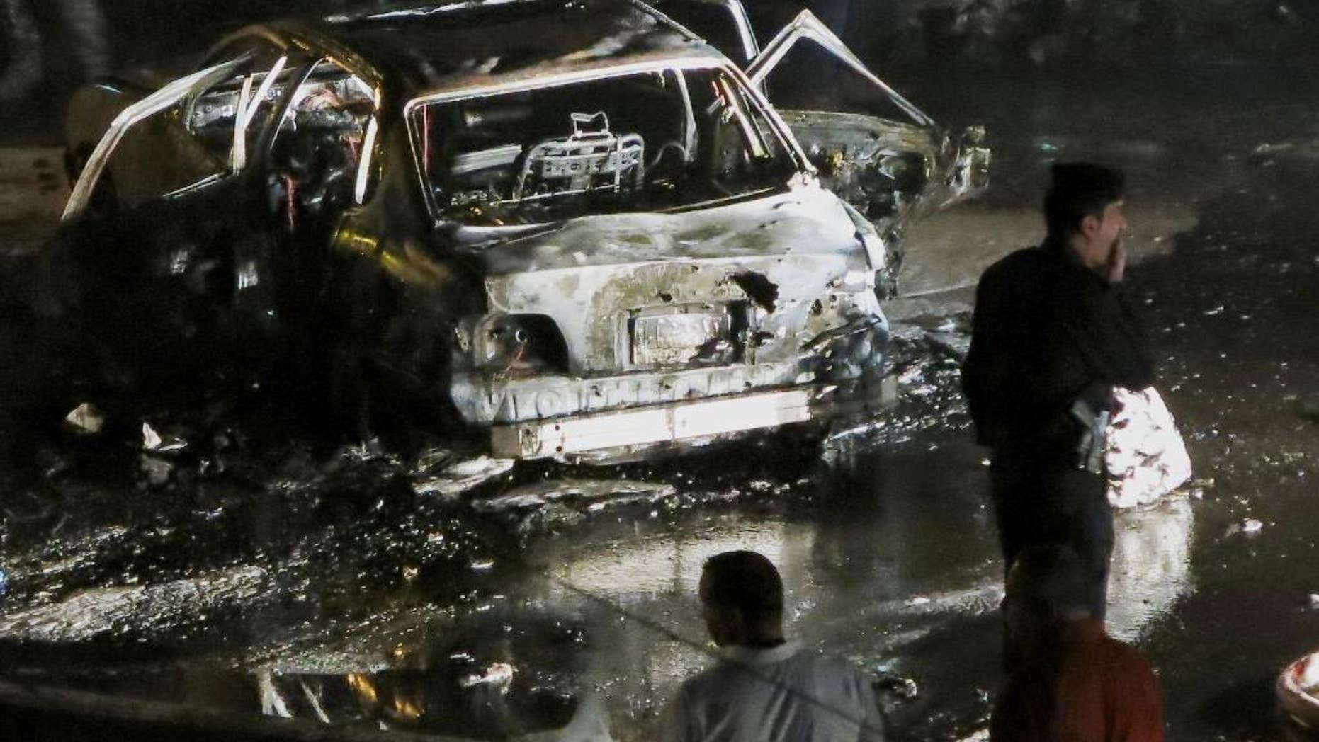 Civilians and security forces gather at the scene of a car bomb explosion in Baghdad's western district of Mansour, Iraq, Monday, April 27, 2015. A series of car bombings targeting busy commercial areas in Iraq's capital left many civilians killed and others wounded, officials said. (AP Photo)