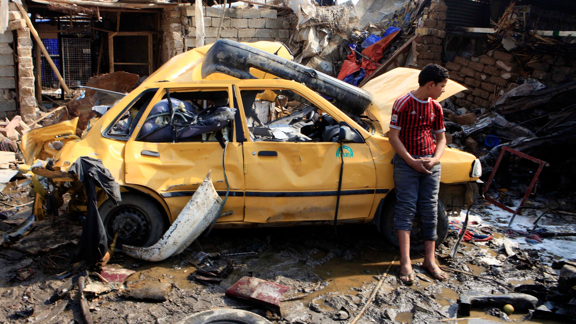 Feb. 8, 2013 - An Iraqi boy stands near a destroyed car at the scene of a car bomb attack in Baghdad's northern Kazimyah neighborhood.