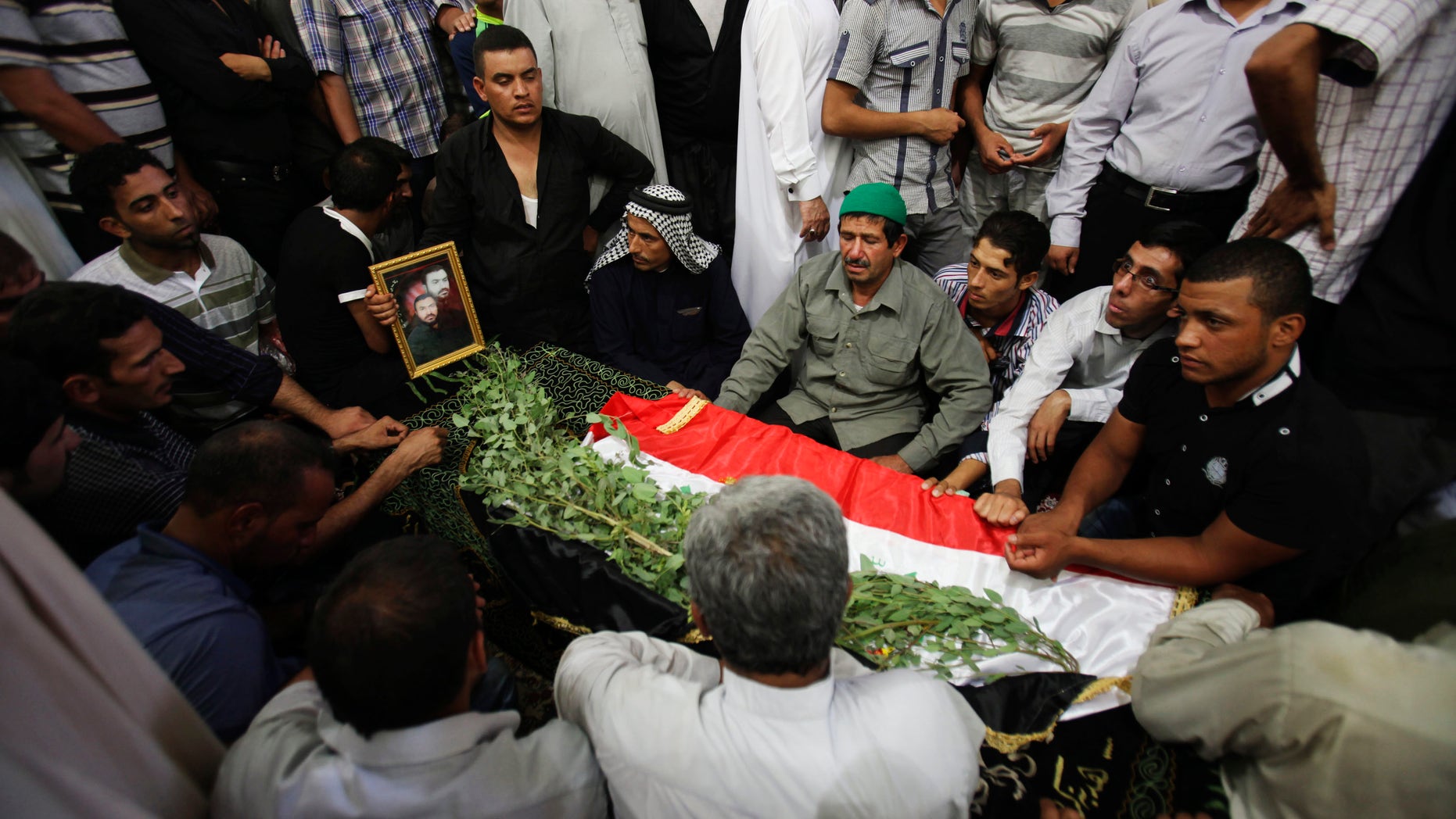 Mourners pray over the coffin a slain Shiite pilgrim during his funeral in the holy city of Karbala, 80 kilometers (50 miles) south of Baghdad, Iraq, Tuesday, Sept. 13, 2011.