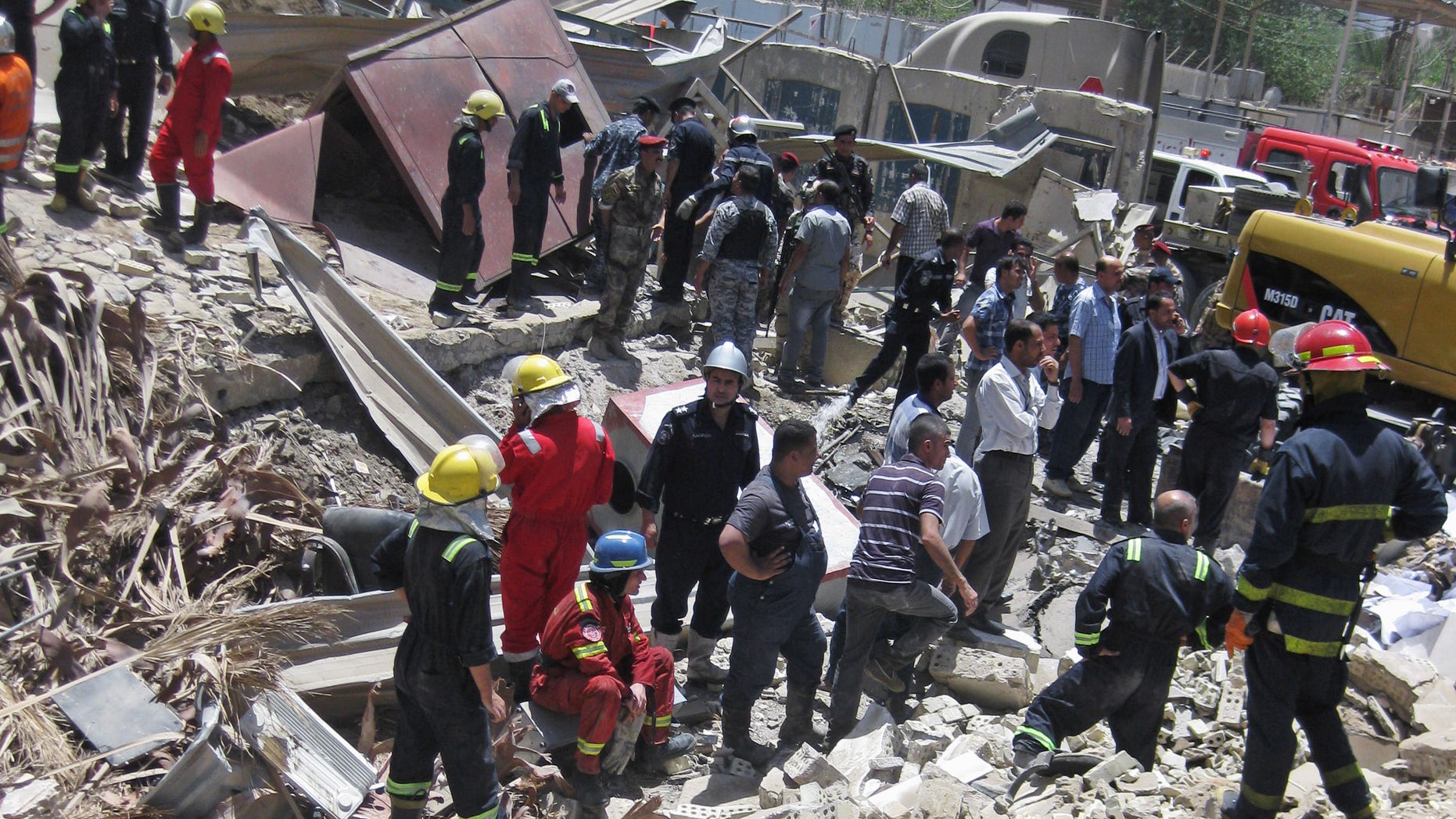 Firefighters and rescuers search for victims at the site of a bomb attack in the central Bab al-Muadham area in Baghdad, Iraq, Monday, June 4, 2012. A suicide bomber detonated explosives in a car outside Iraq's main religious affairs office for Shiite Muslims tearing down part of the three-story building and killed and wounded scores of people, police said. (AP Photo/Hadi Mizban)