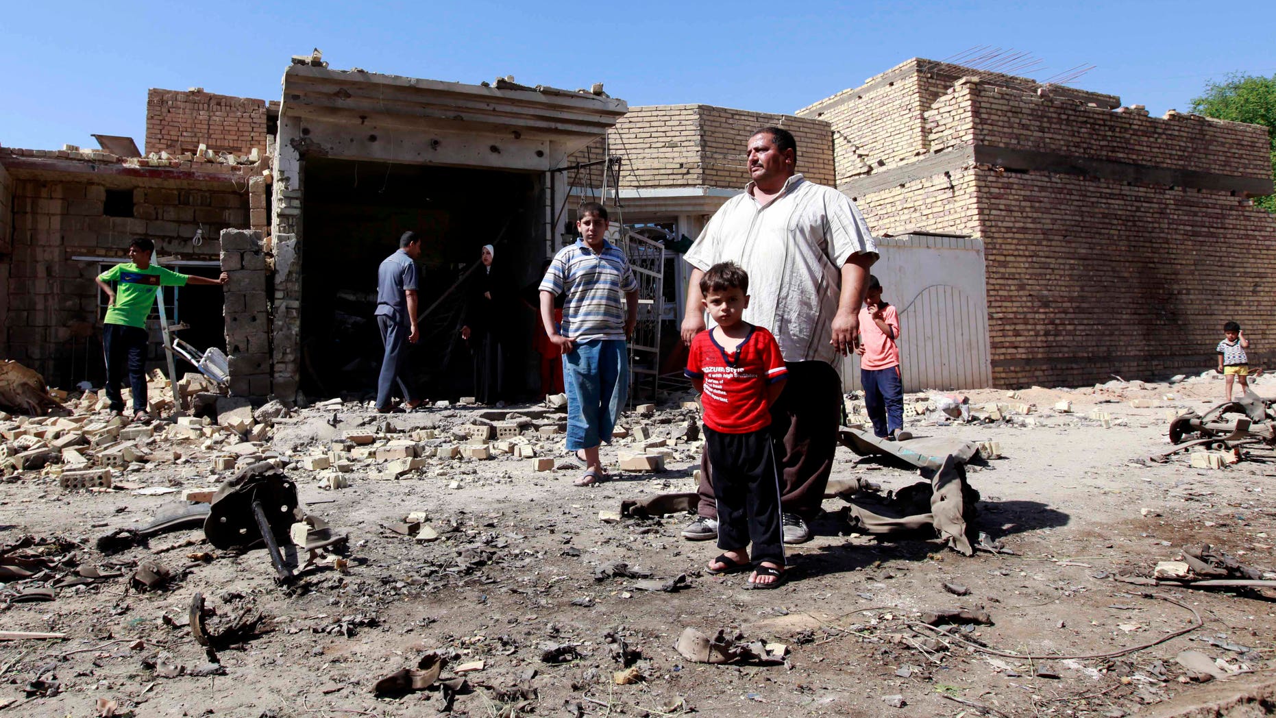 Sept. 30, 2012 - Iraqis stand in rubble at the scene of a car bomb attack in the town of Taji, about 12 miles north of Baghdad, Iraq.
