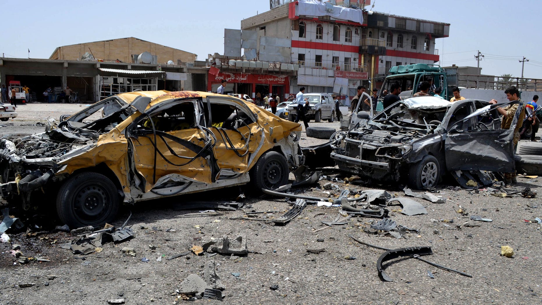 June 9, 2014 - Civilians and security forces inspect the site of a suicide attack in Tuz Khormato, 130 miles north of Baghdad, Iraq. A suicide bomber drove his explosive-laden truck into a checkpoint leading up to the offices of the Patriotic Union of Kurdistan and the nearby Kurdistan Communist Party. As people rushed to the site of the explosion, another truck bomb exploded, presumably detonated by remote control.
