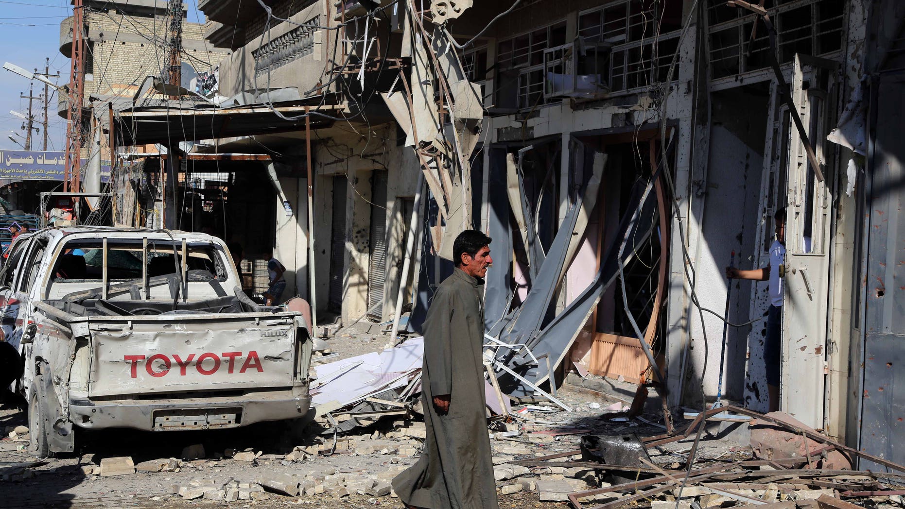 March 23, 2015 - A man inspects the site of a car bomb explosion in a busy commercial street at the Habibiya section of Baghdad's Sadr City, Iraq. Multiple bombings in the Iraqi capital killed and wounded many, Iraqi officials said.