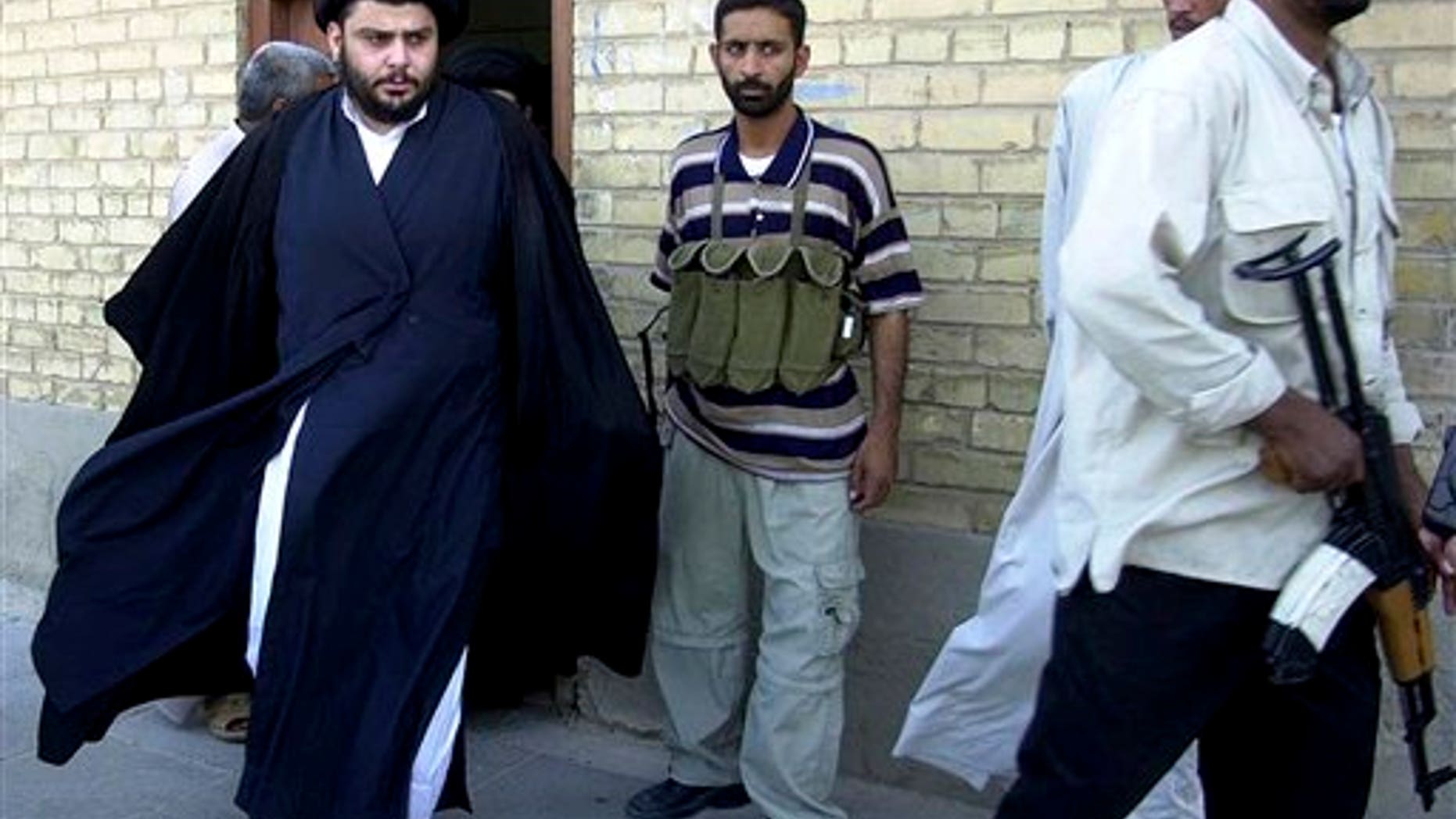 June 5, 2004: Shiite cleric Muqtada al-Sadr, left, steps from an office building in Najaf, Iraq.